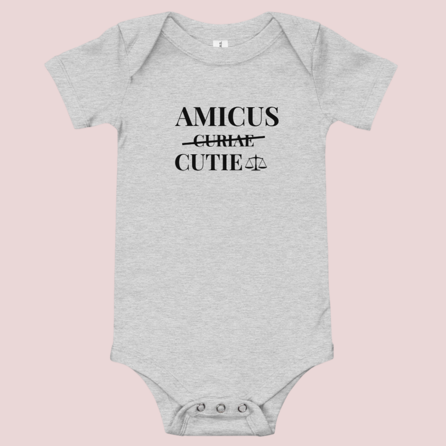 A grey infant onesie featuring in black text, the words "AMICUS", "CUTIE", and a stricken out word "CURIAE", with an illustration of justice scales.