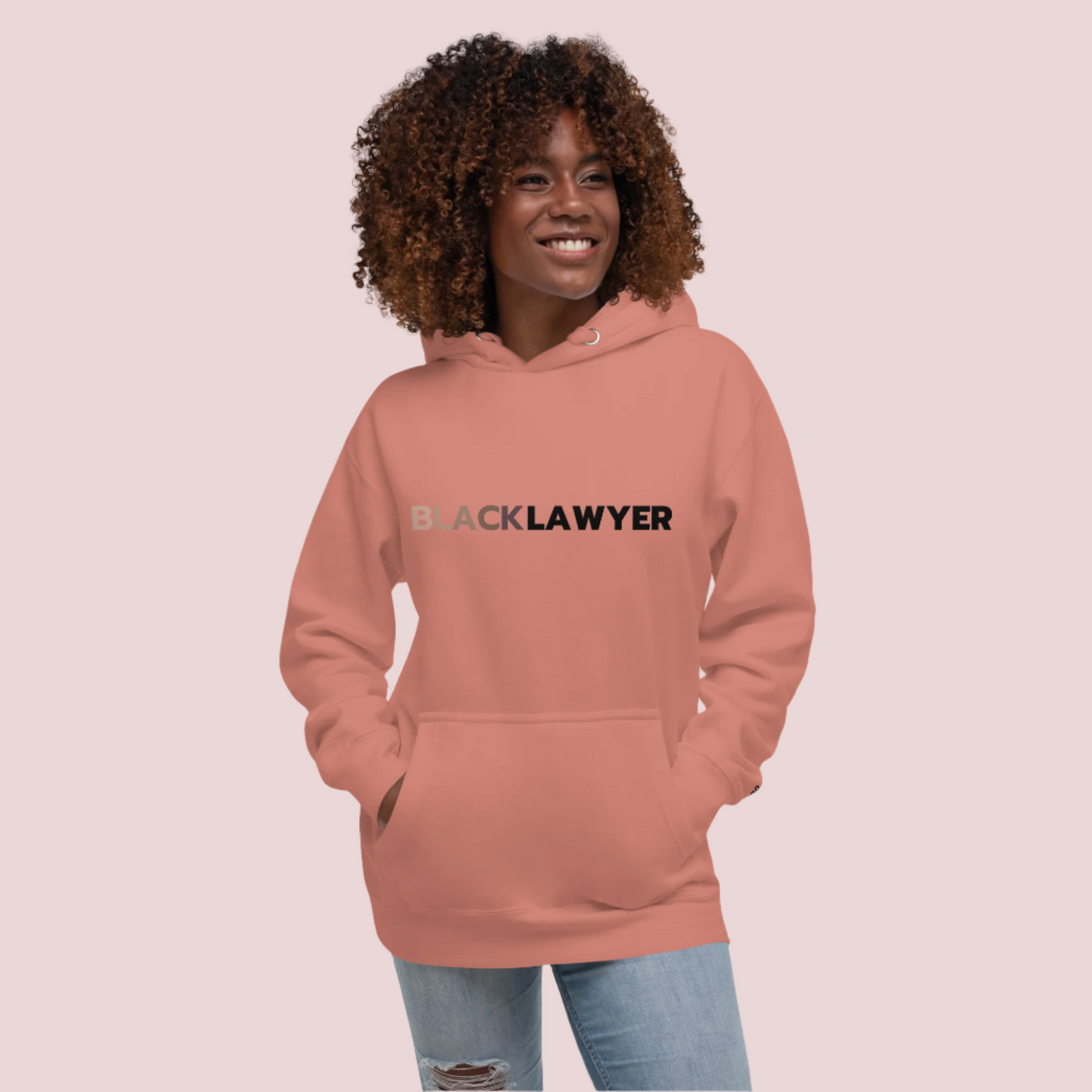 A model wearing jeans and a pink hoodie with the words "Black Lawyer" on it.