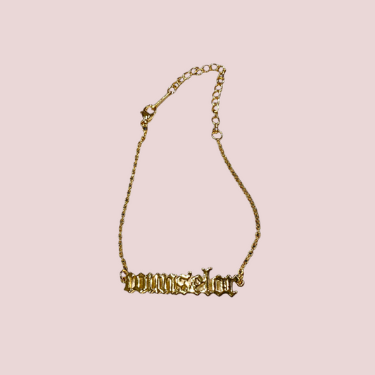 A gold chain bracelet featuring the word "counselor" in old English text.