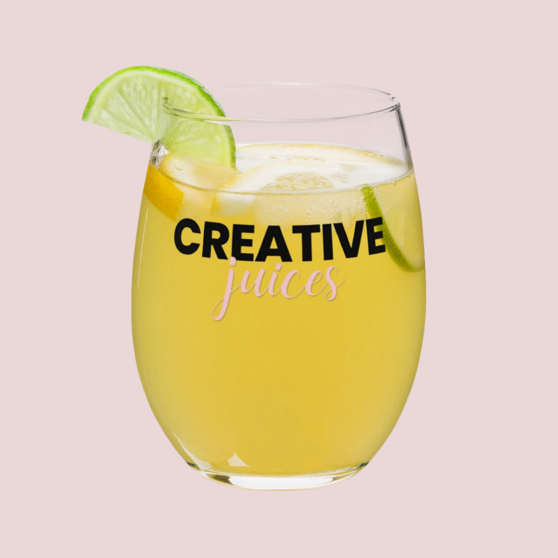 A stemless wine glass with the text "creative juices" on the front. A lime is on the rim and there is a cocktail in the glass.