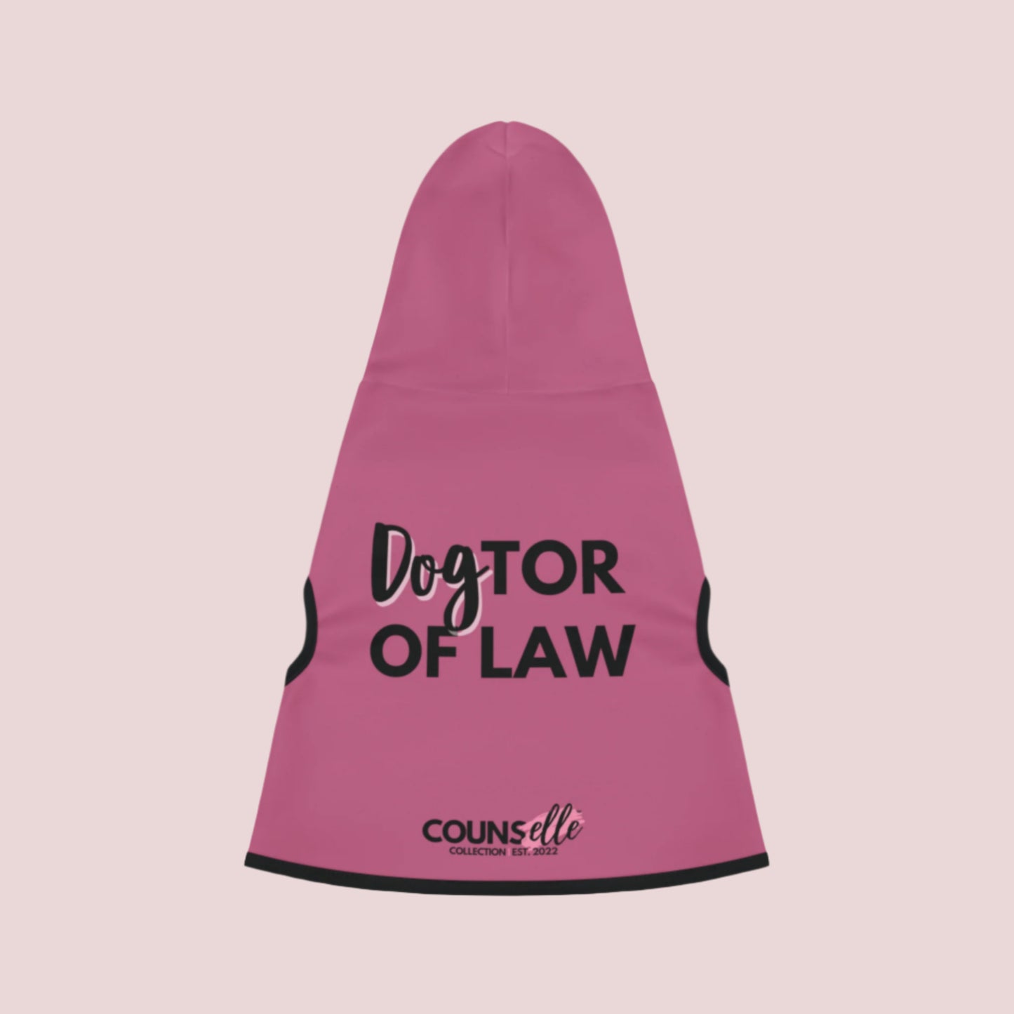 A pink pet hoodie with black cuffs and hem accents, featuring the words "DogTOR OF LAW" and the counsellecollection logo near the hemline.