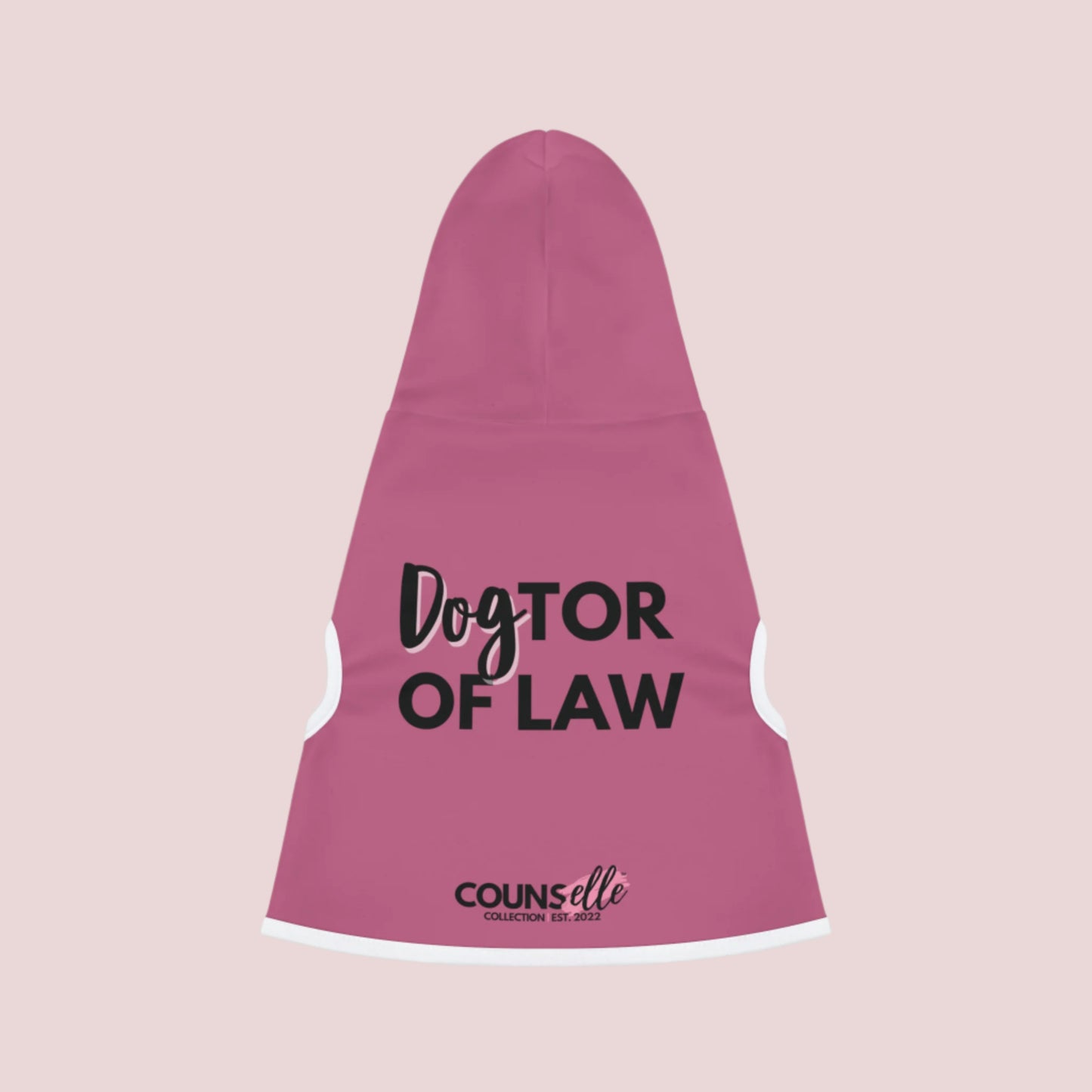 A pink pet hoodie with white cuffs and hem accents, featuring the words "DogTOR OF LAW" and the counsellecollection logo near the hemline.