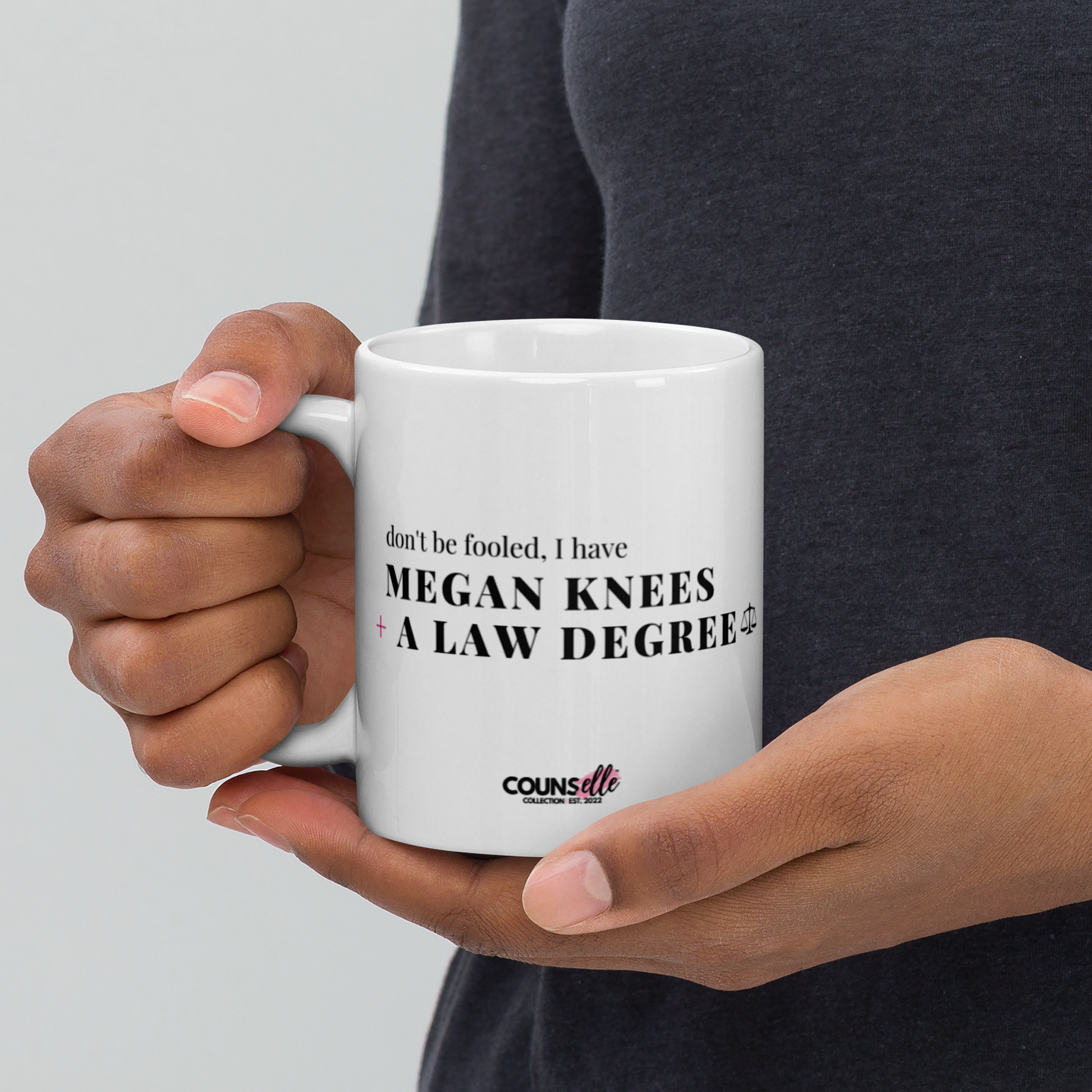 A ceramic mug with the text "DON'T BE FOOLED, I'VE GOT MEGAN KNEES AND A LAW DEGREE" on the front.