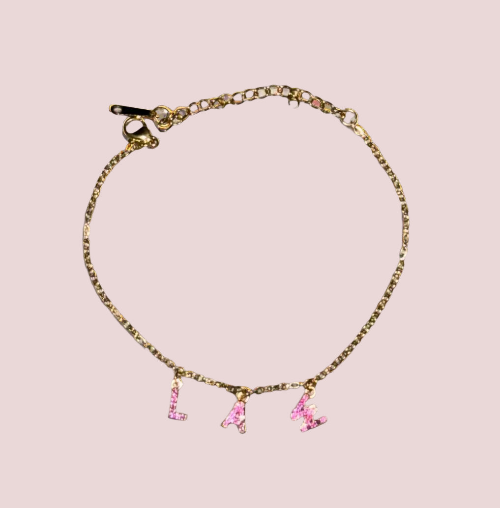 A bracelet with the word "LAW" in hot pink stones as charms.