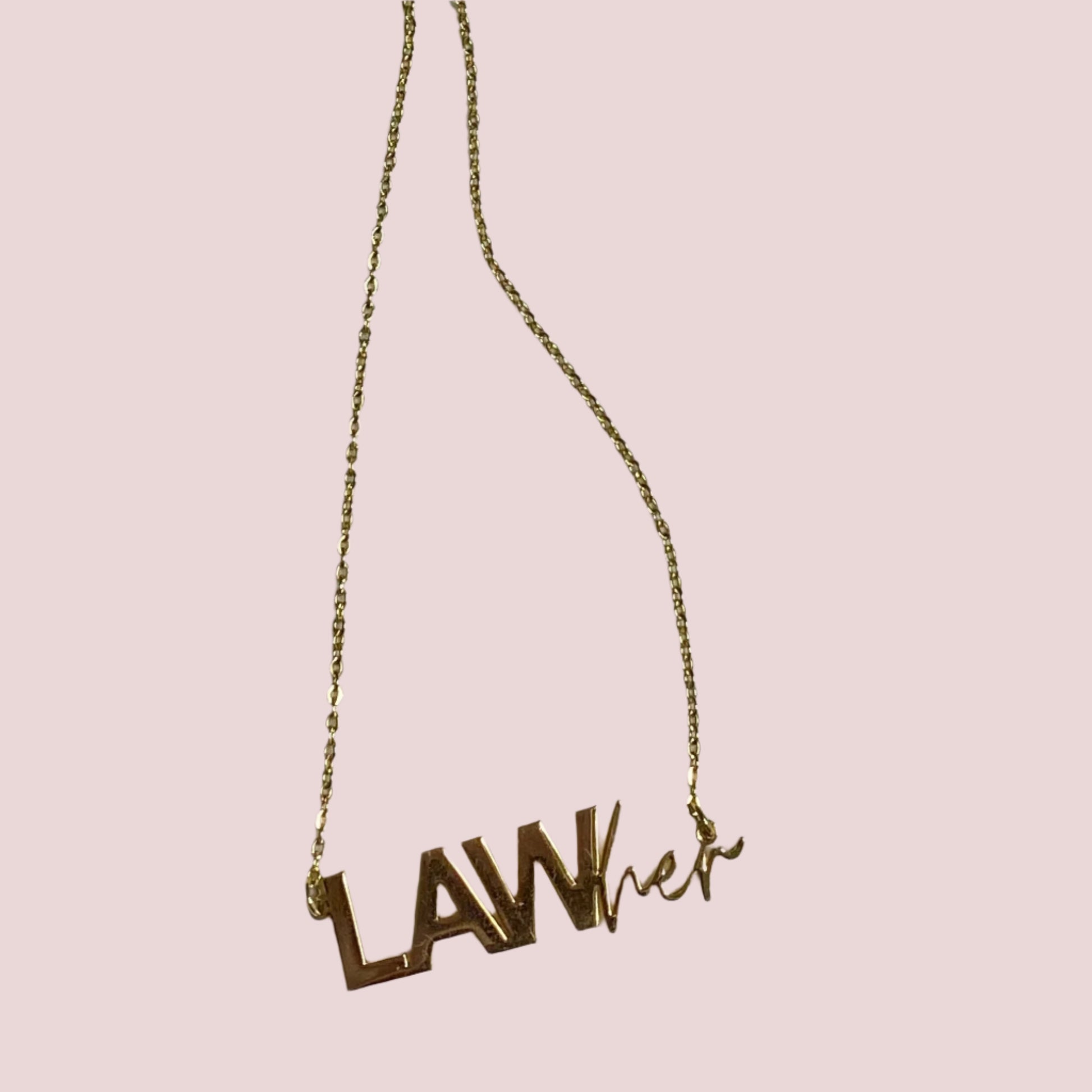 A gold necklace with a pendant/charm featuring the words "LAW" in block text and "her" in script.