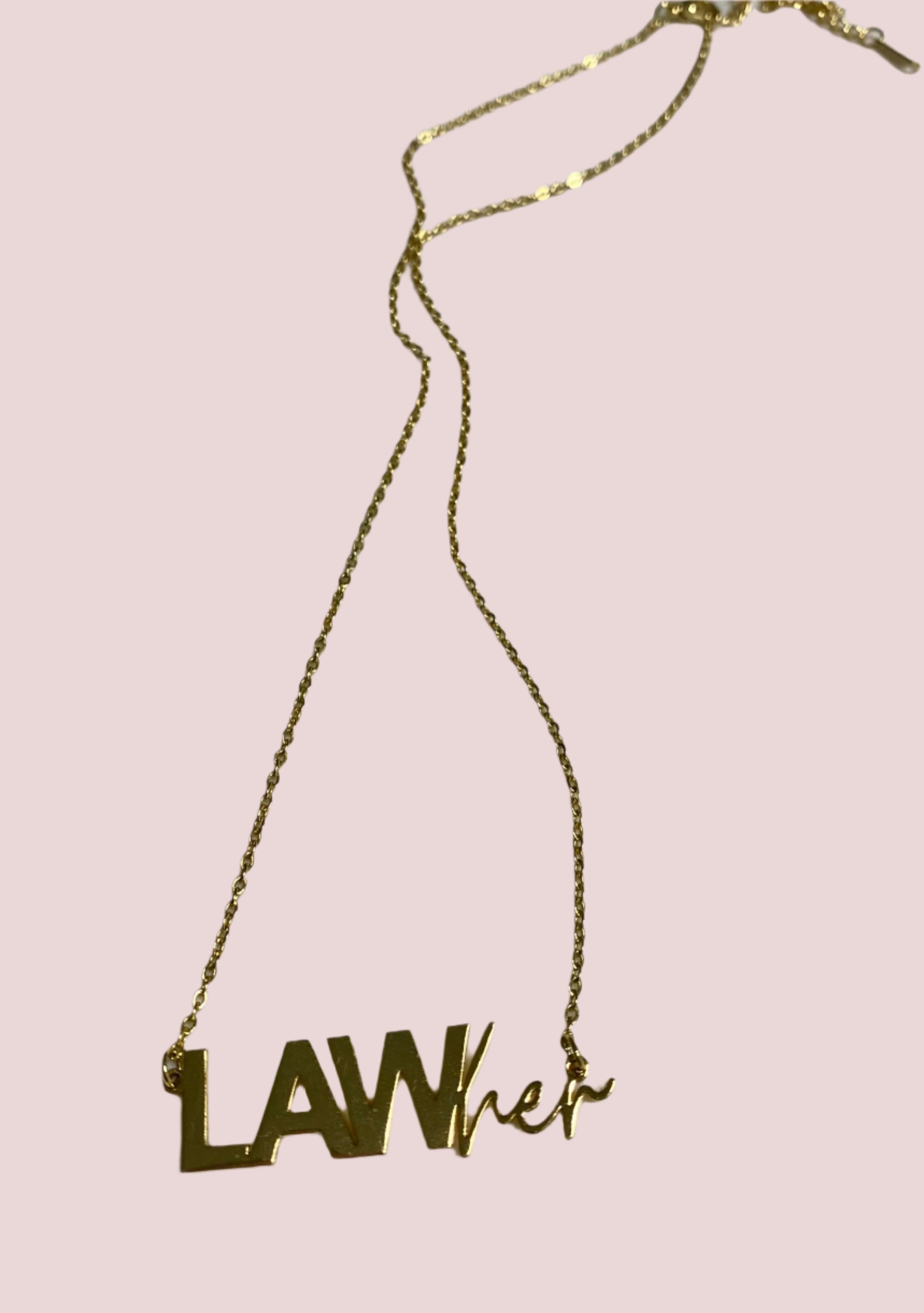 A gold necklace with a pendant/charm featuring the words "LAW" in block text and "her" in script.