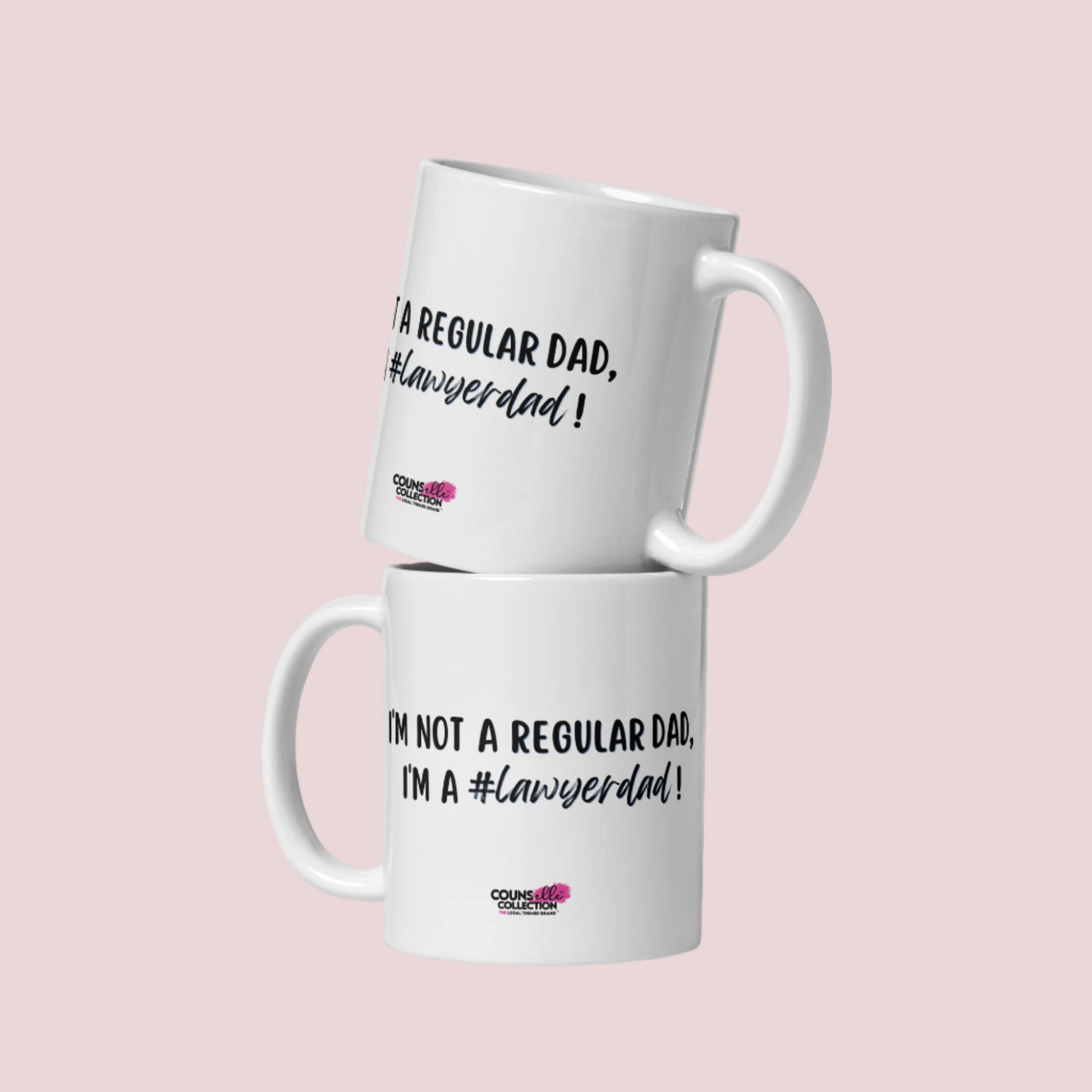 Two stacked white mugs with the text "I'm not a regular dad, I'm a #lawyerdad!"  and the counsellecollection logo at the bottom of the design.