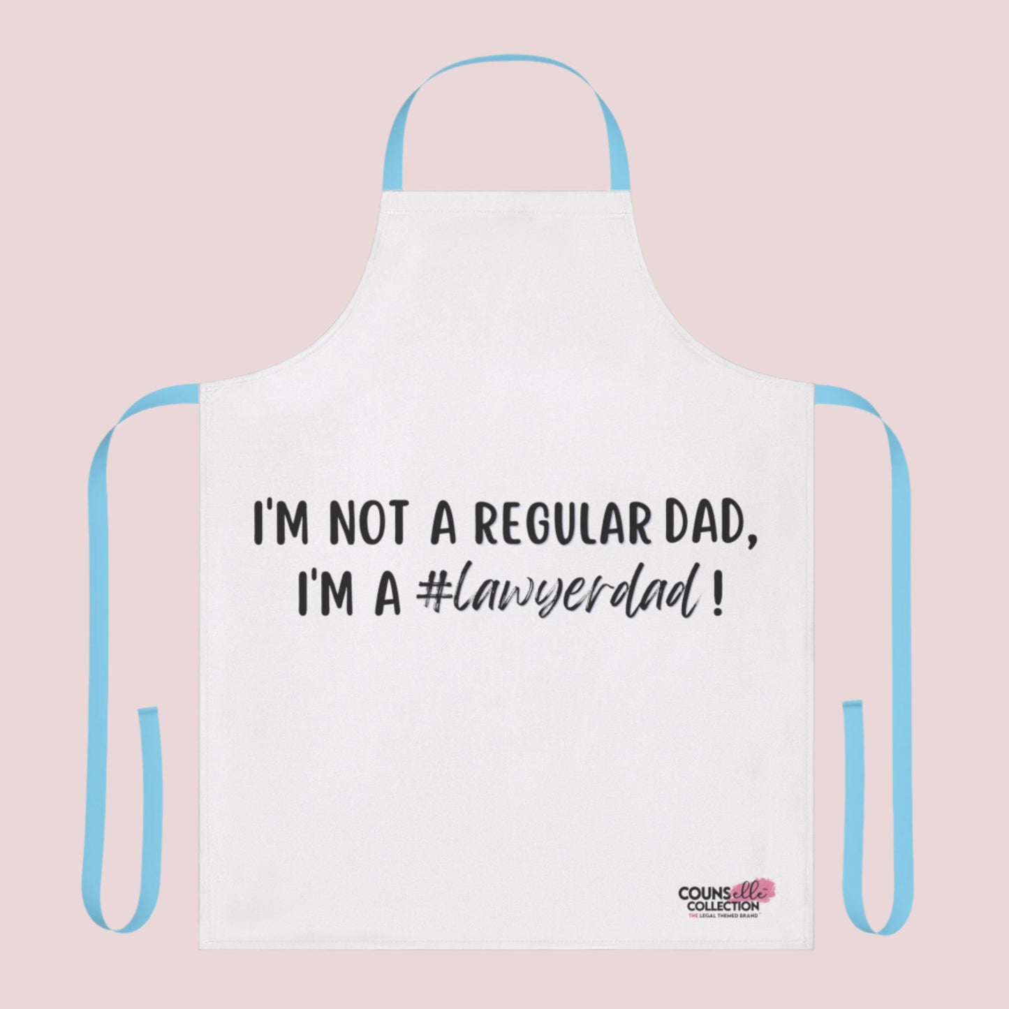 A white apron with the text "I'm not a regular dad, I'm a #lawyerdad!" and the counsellecollection logo on the bottom right corner. The apron has a blue neck strap and belt.
