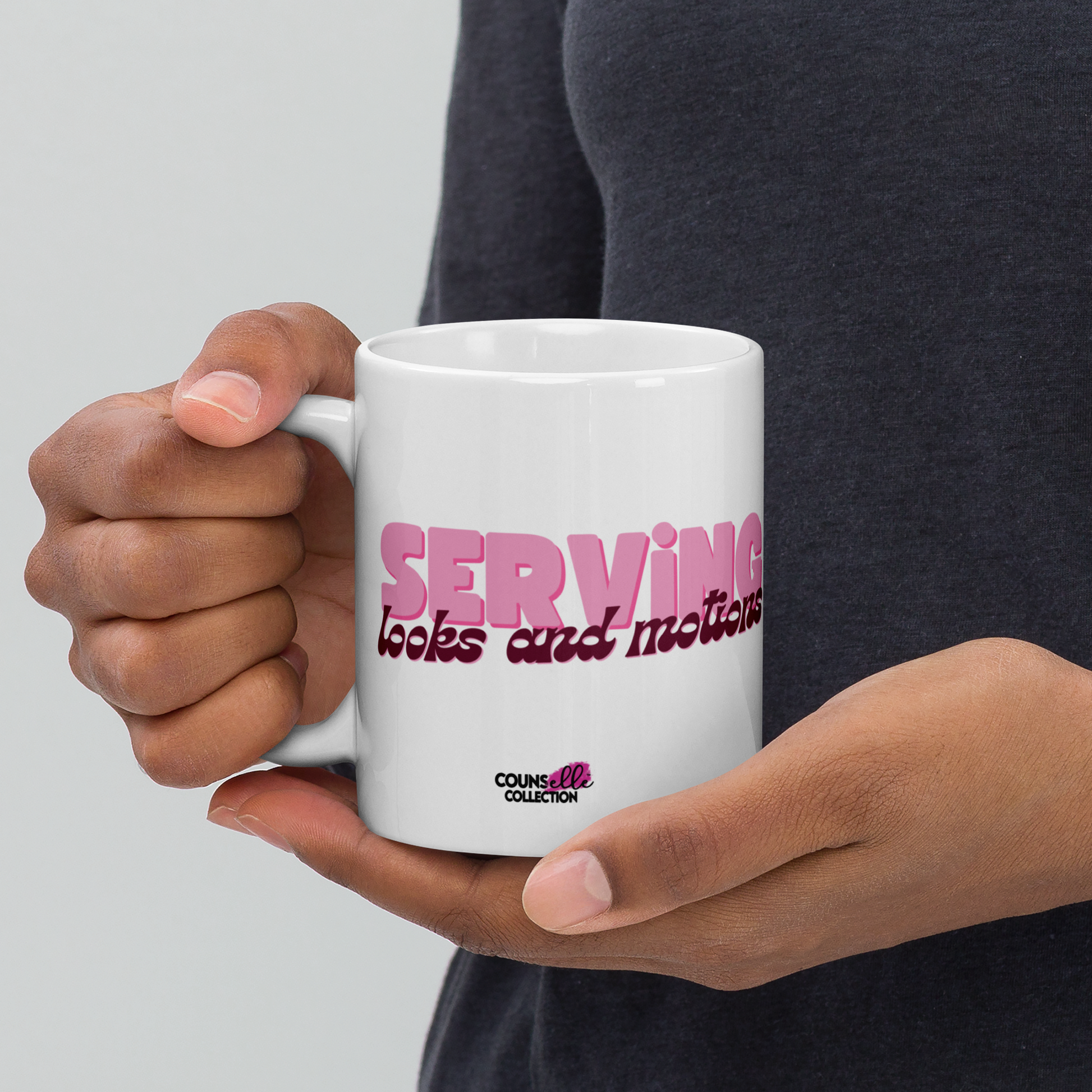 A model holding a white mug featuring the words "serving looks and motions" in pink and burgundy letters.