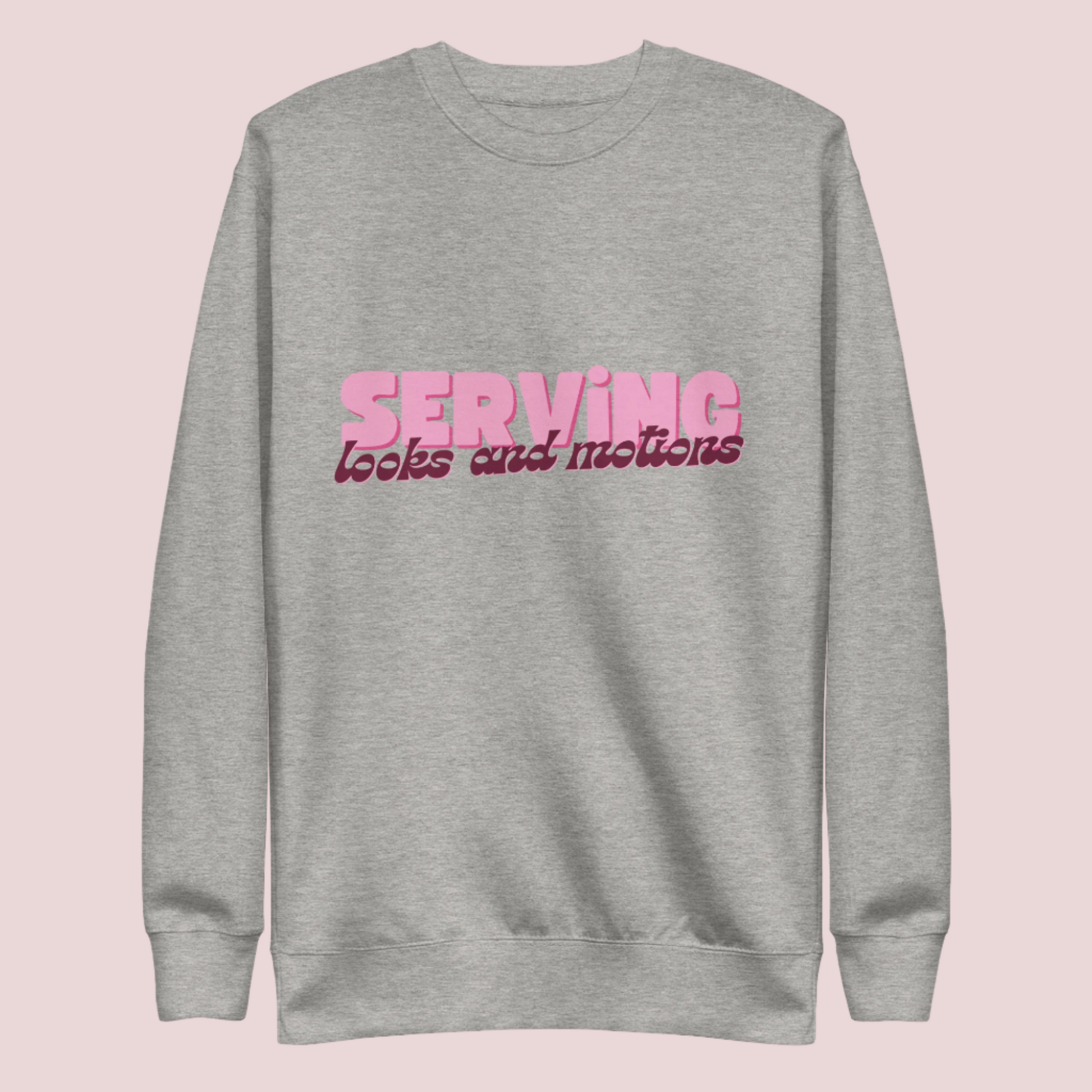 A grey sweatshirt showing the text "SERVING looks and motions" in pink font.