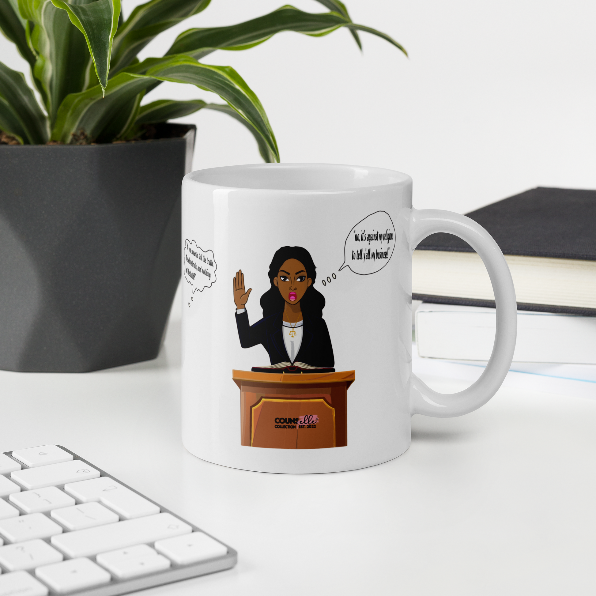 A white mug sitting on a desk with a plant, a book and a keyboard. The mug features an illustration of a black woman with her hand raised, testifying in court. Speech bubble that says "It's against my religion to tell yall my business."