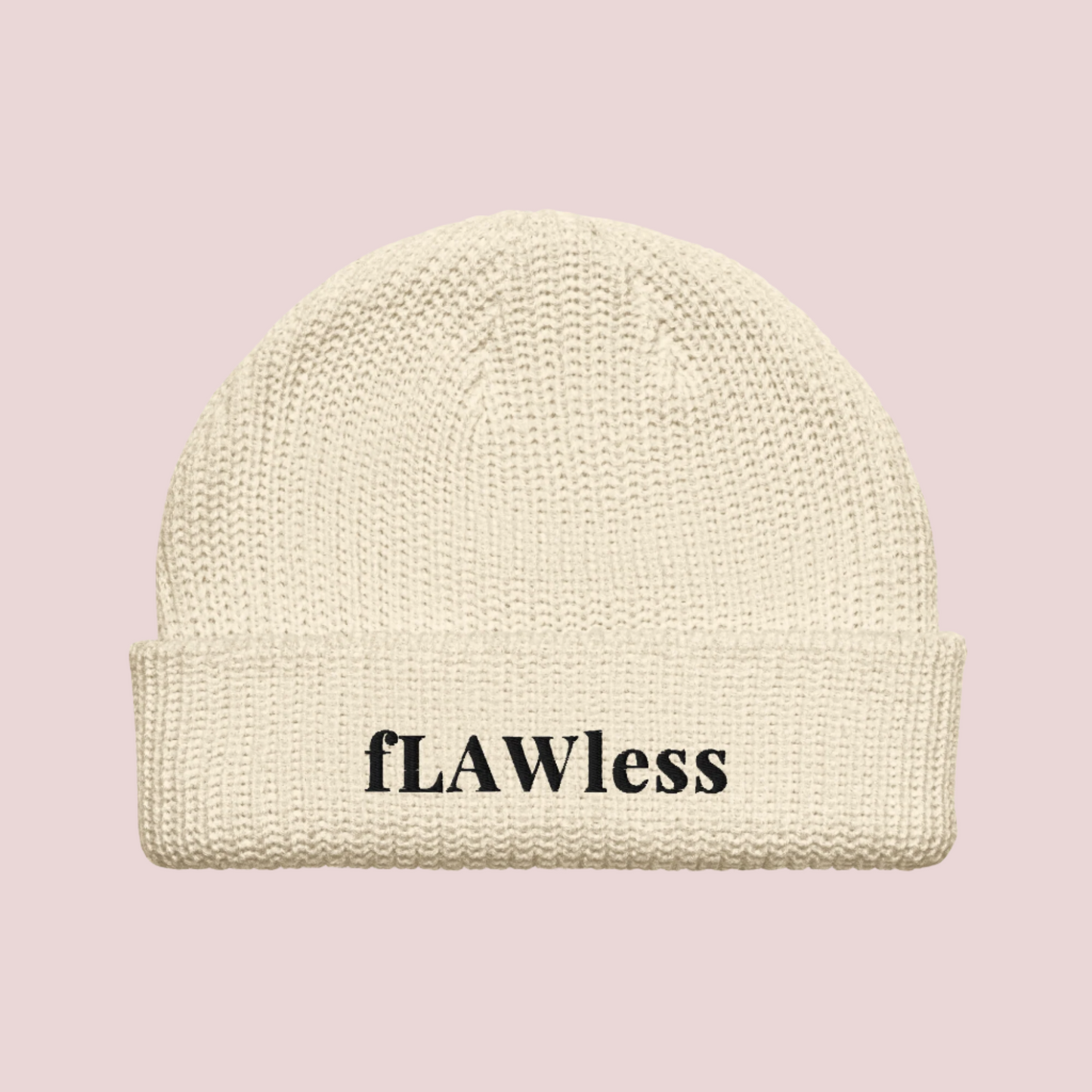 A cream beanie with the text "fLAWless" in black text written on it.
