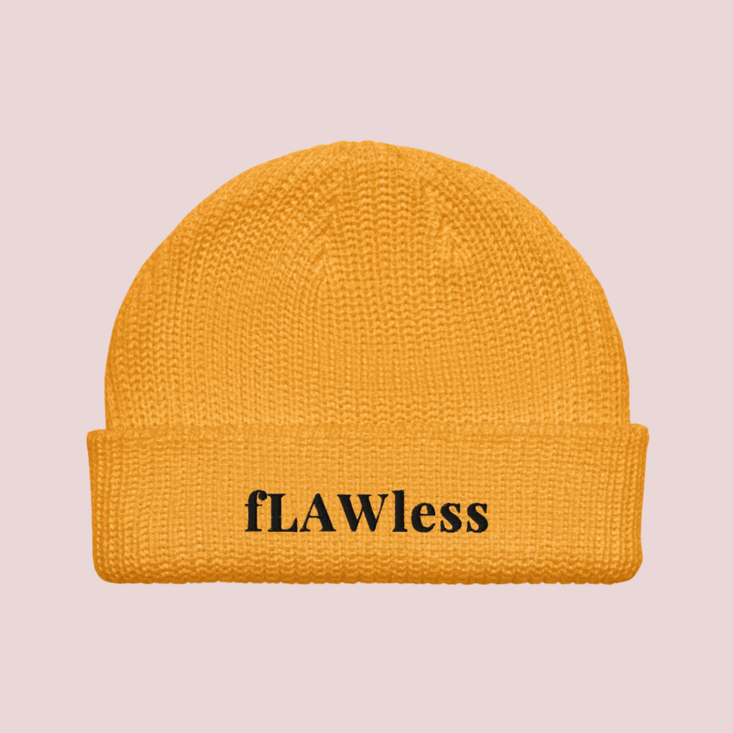 A golden yellow beanie with the text "fLAWless" in black text written on it.