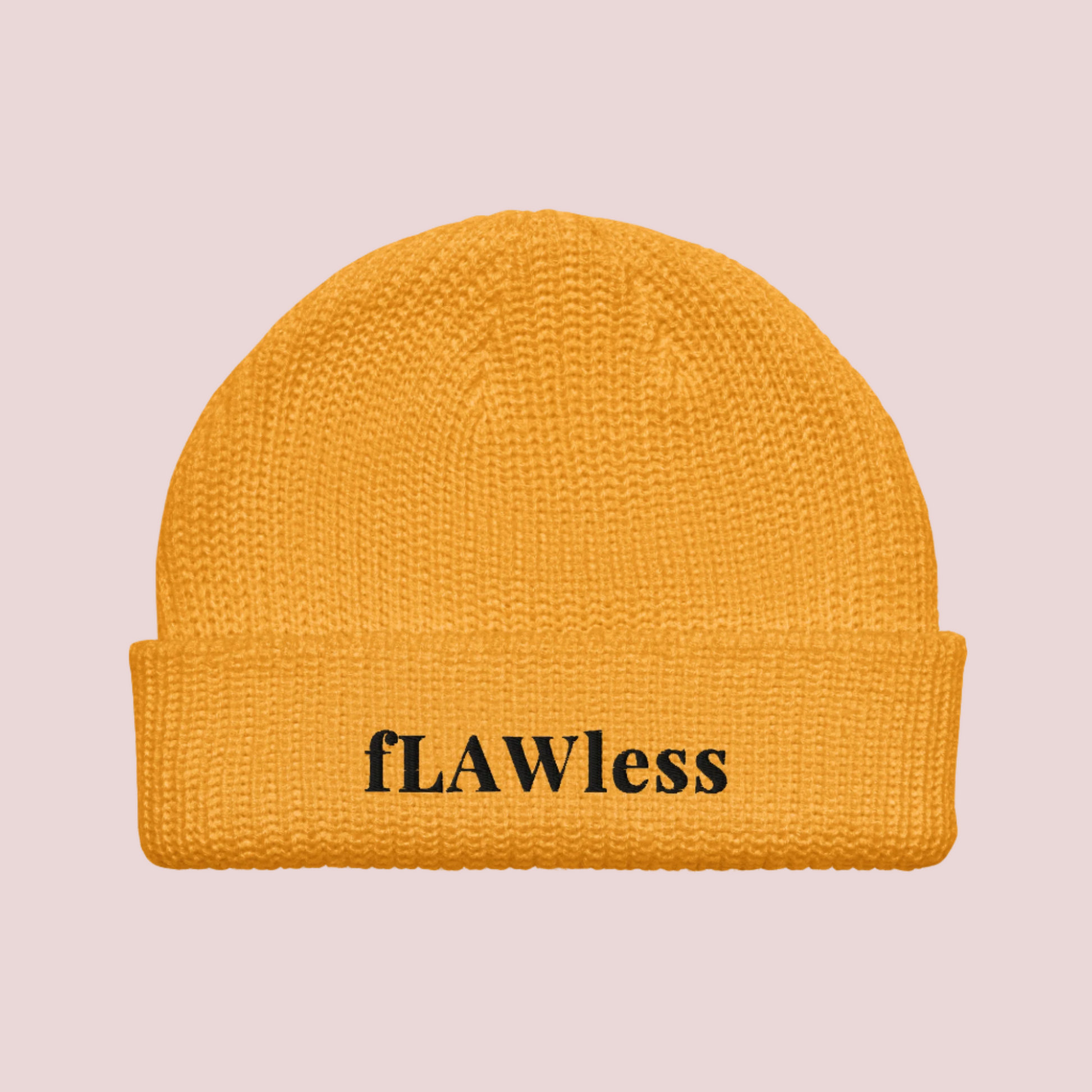 A golden yellow beanie with the text "fLAWless" in black text written on it.