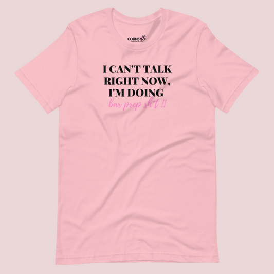 A pink roundneck tee showing the text "I CAN'T TALK RIGHT NOW, I'M DOING BAR PREP SH*T!"
