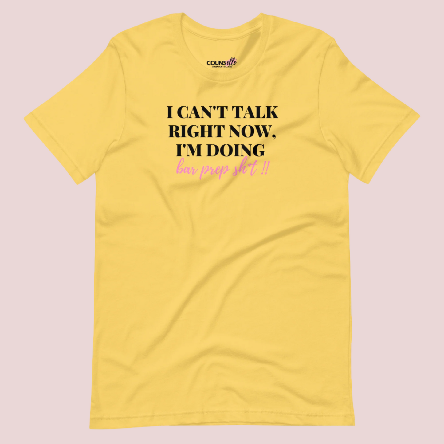 A yellow roundneck tee showing the text "I CAN'T TALK RIGHT NOW, I'M DOING BAR PREP SH*T!"