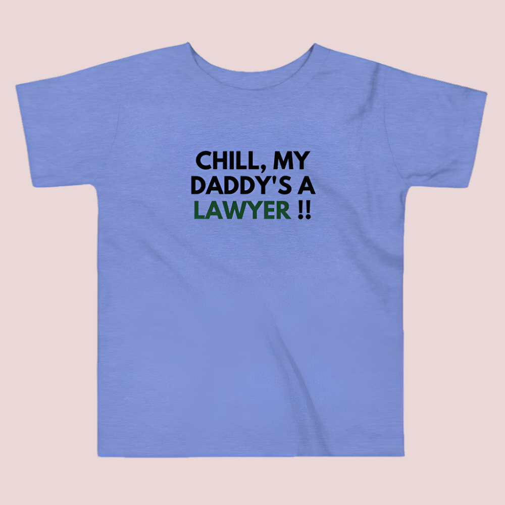 A blue roundneck kid's tee featuring the quote "Chill my daddy's a lawyer" in uppercase text.