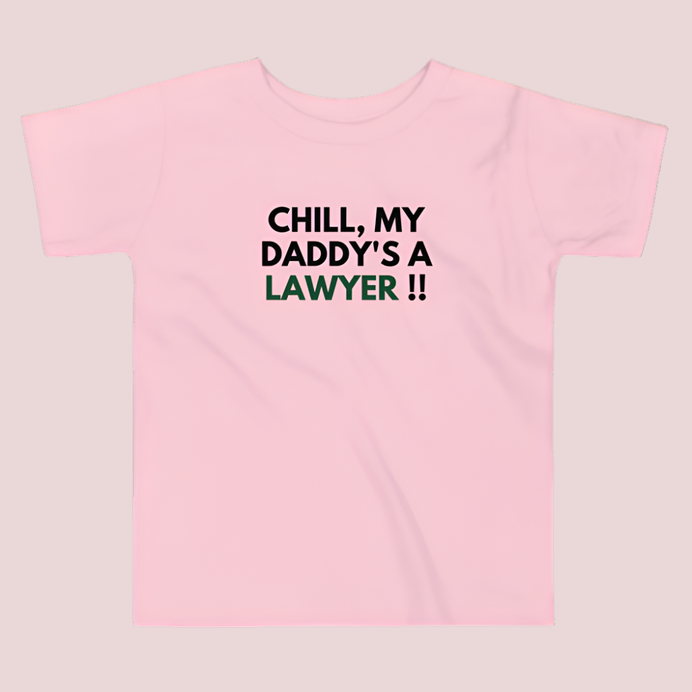 A pink roundneck kid's tee featuring the quote "Chill my daddy's lawyer" in uppercase text.