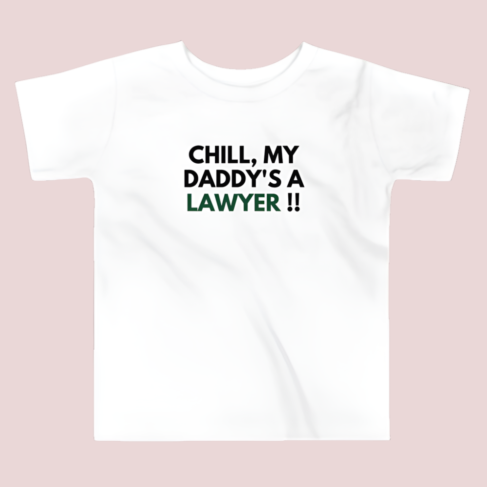 A white roundneck kid's tee featuring the quote "Chill my daddy's lawyer" in uppercase text.