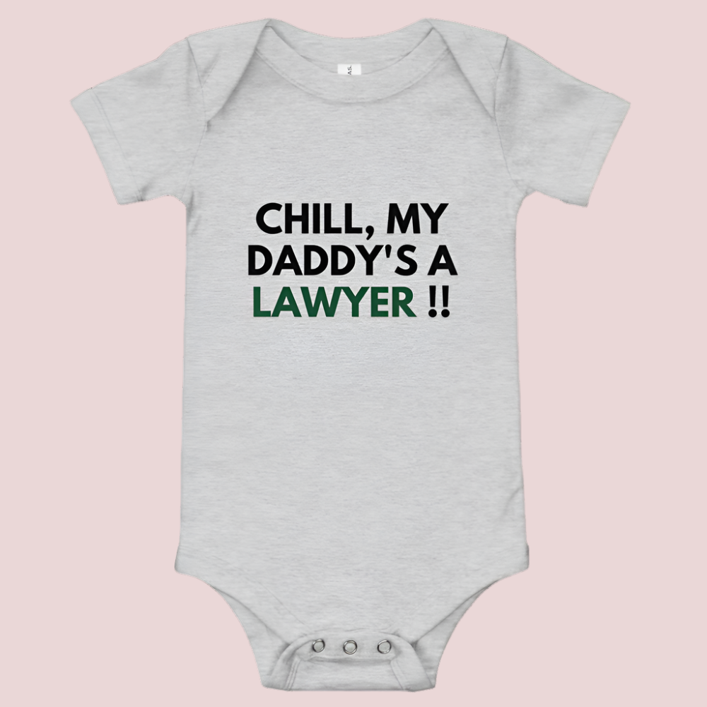 A grey baby onesie with a three-snap leg closure featuring the quote "Chill my daddy's a lawyer" in uppercase block text.