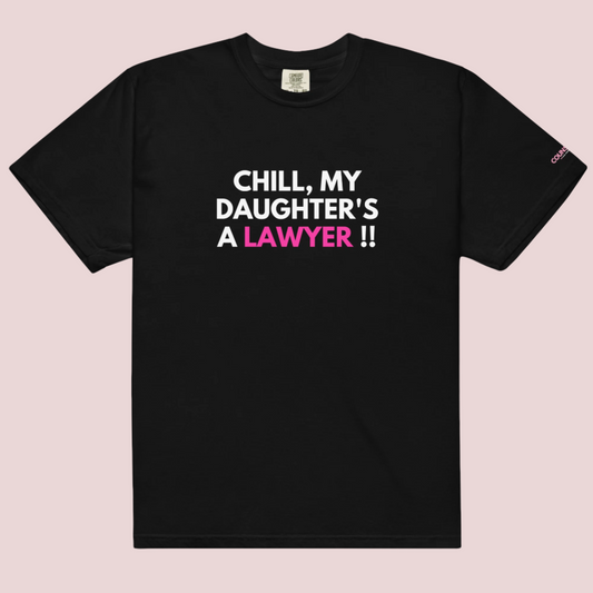 A black roundneck t-shirt with the slogan "CHILL MY DAUGHTER'S A LAWYER." and the counsellecollection logo on the left sleeve.