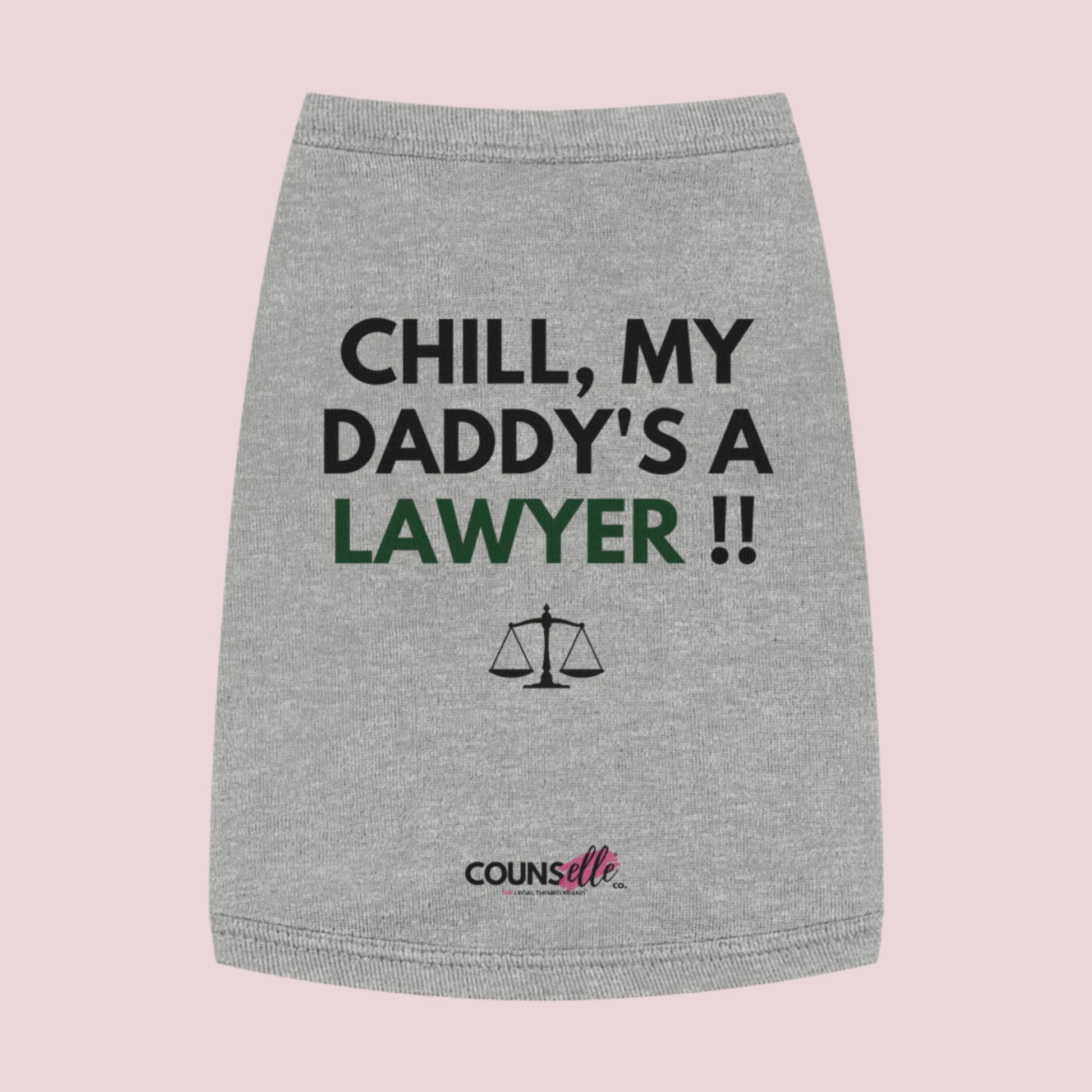 A grey pet tee featuring the quote "Chill, my daddy's a lawyer" in uppercase text, an illustration of justice scales below the text and the counsellecollection logo near the hem.