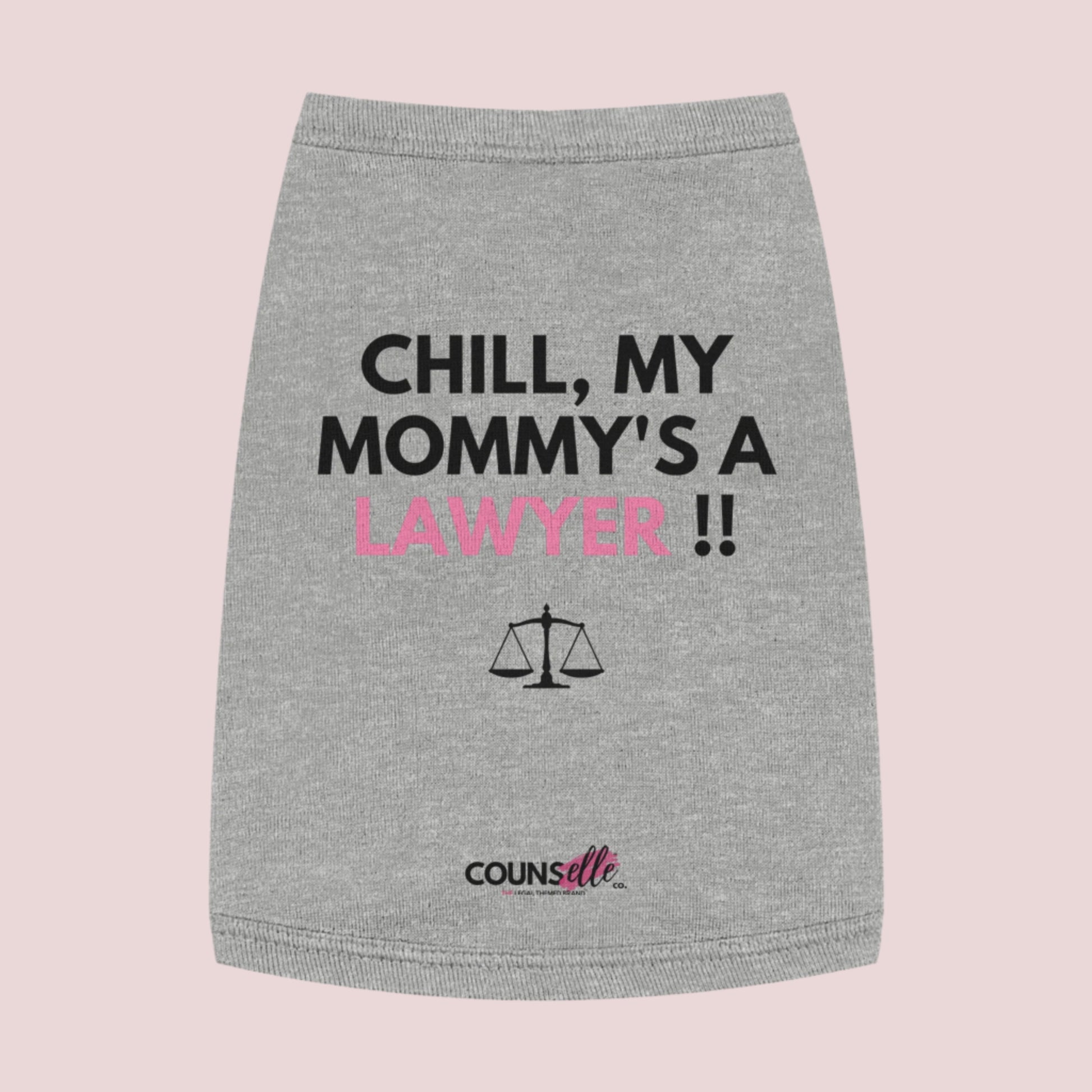 A grey pet tee featuring the quote "Chill, my mommy's a lawyer" in uppercase text, an illustration of justice scales below the text and the counsellecollection logo near the hem.