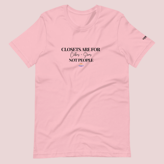 A pink crewneck tee with the text "CLOSETS ARE FOR CLOTHES + SHOES NOT PEOPLE" in black font, with an illustration of a rainbow justice scales underneath. The counsellecollection logo is seen on the left sleeve.