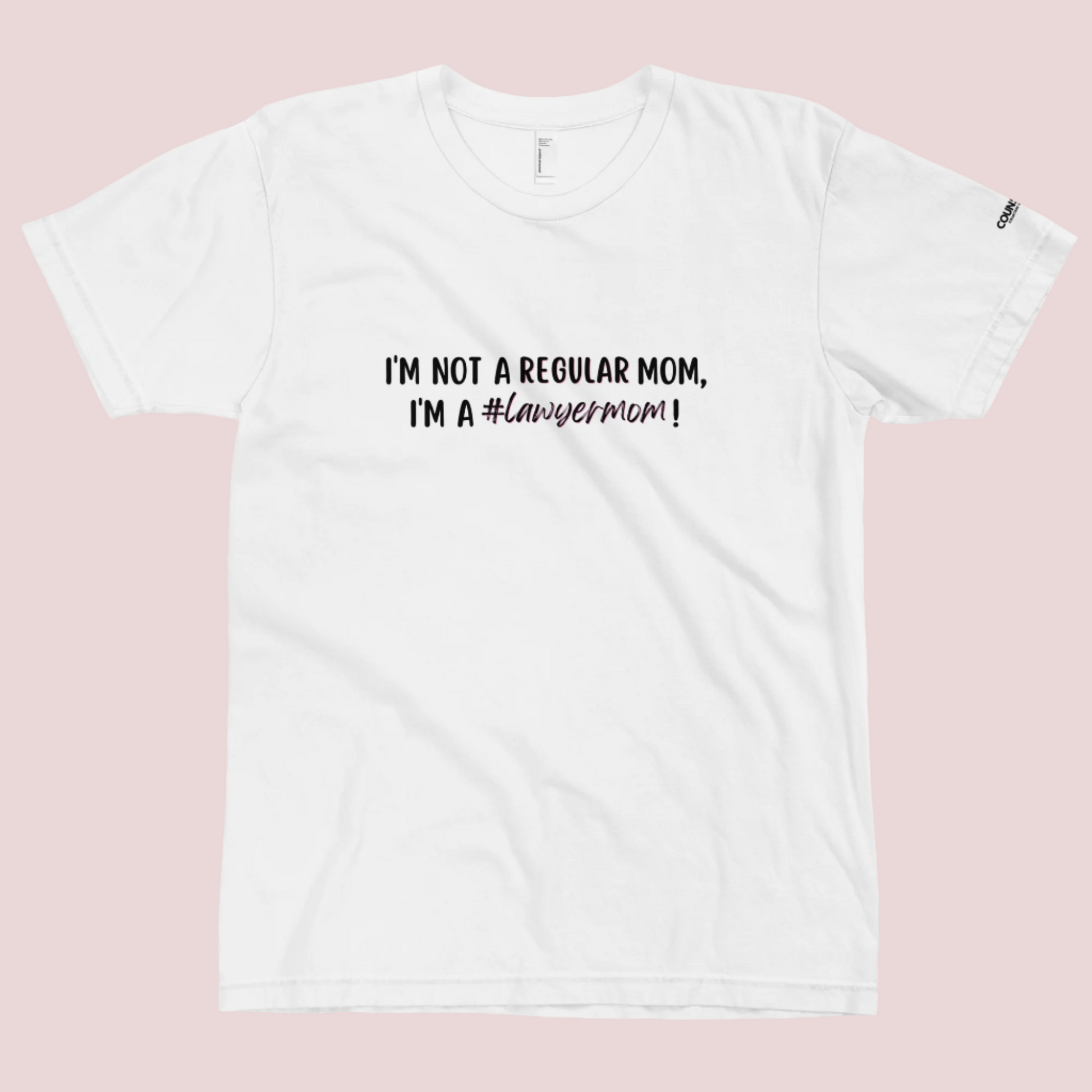 A white round-neck tee with the text "I'M NOT A REGULAR MOM, I'M A #LawyerMom!" in black" text and the counsellecollection logo on the left sleeve.