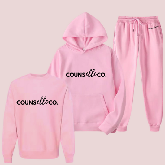 A pink three-piece set of a long-sleeved shirt, hoodie, and sweatpants showing the text "counselleco" in black font.