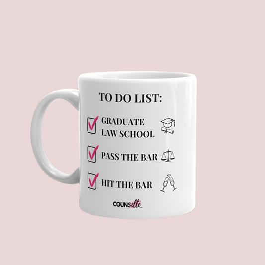 A white mug showing the text "TO DO LIST", with ticked-off boxes beside the texts "GRADUATE LAW SCHOOL" and an illustration of a graduation cap and diploma; "PASS THE BAR" ans an illustration of justice scales; and "HIT THE BAR" and an illustration of clinking champagne flutes. The counsellecollection logo is seen at the bottom of the design.