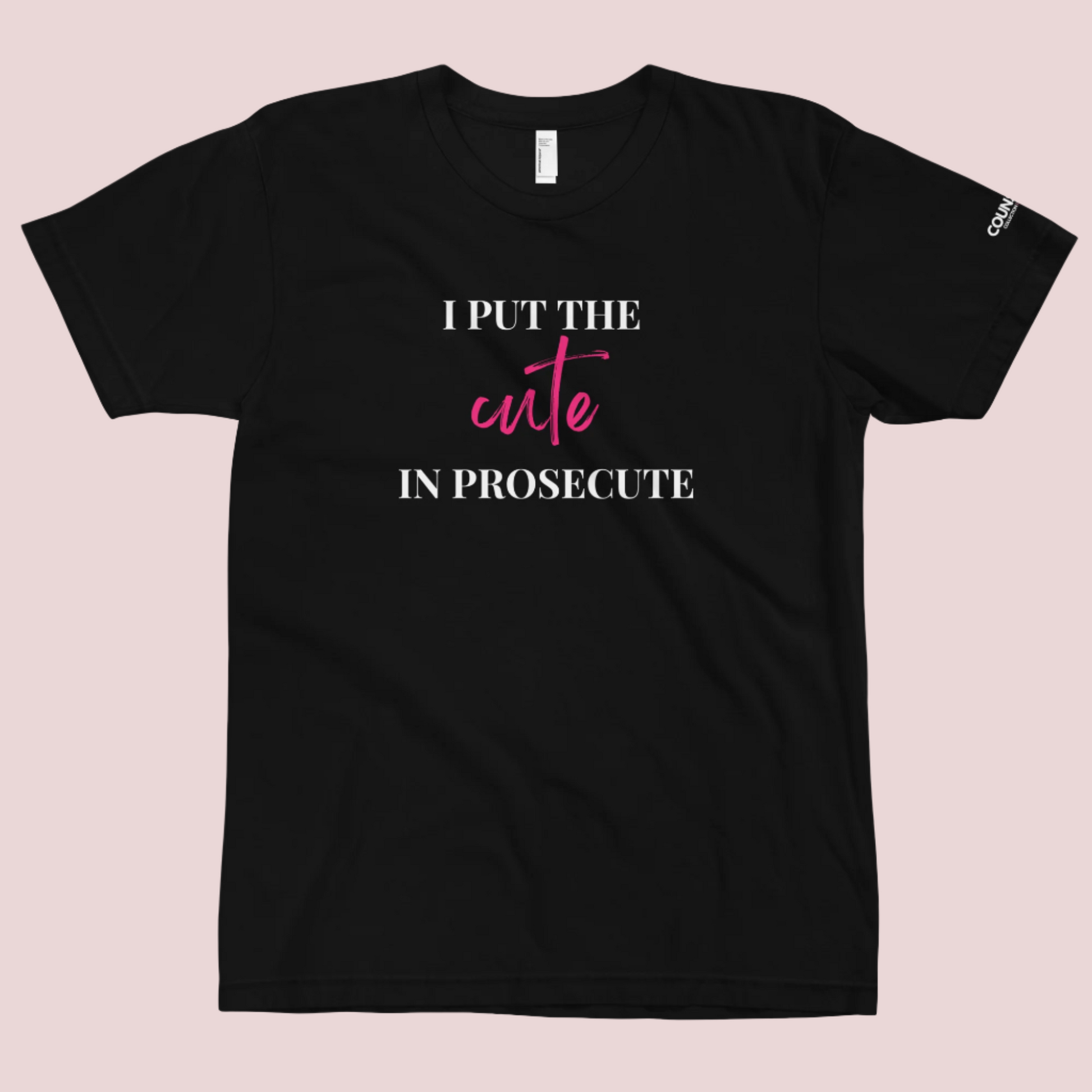 A black round-neck tee with the text "I PUT THE CUTE IN PROSECUTE" and the counsellecollection logo on the left sleeve.