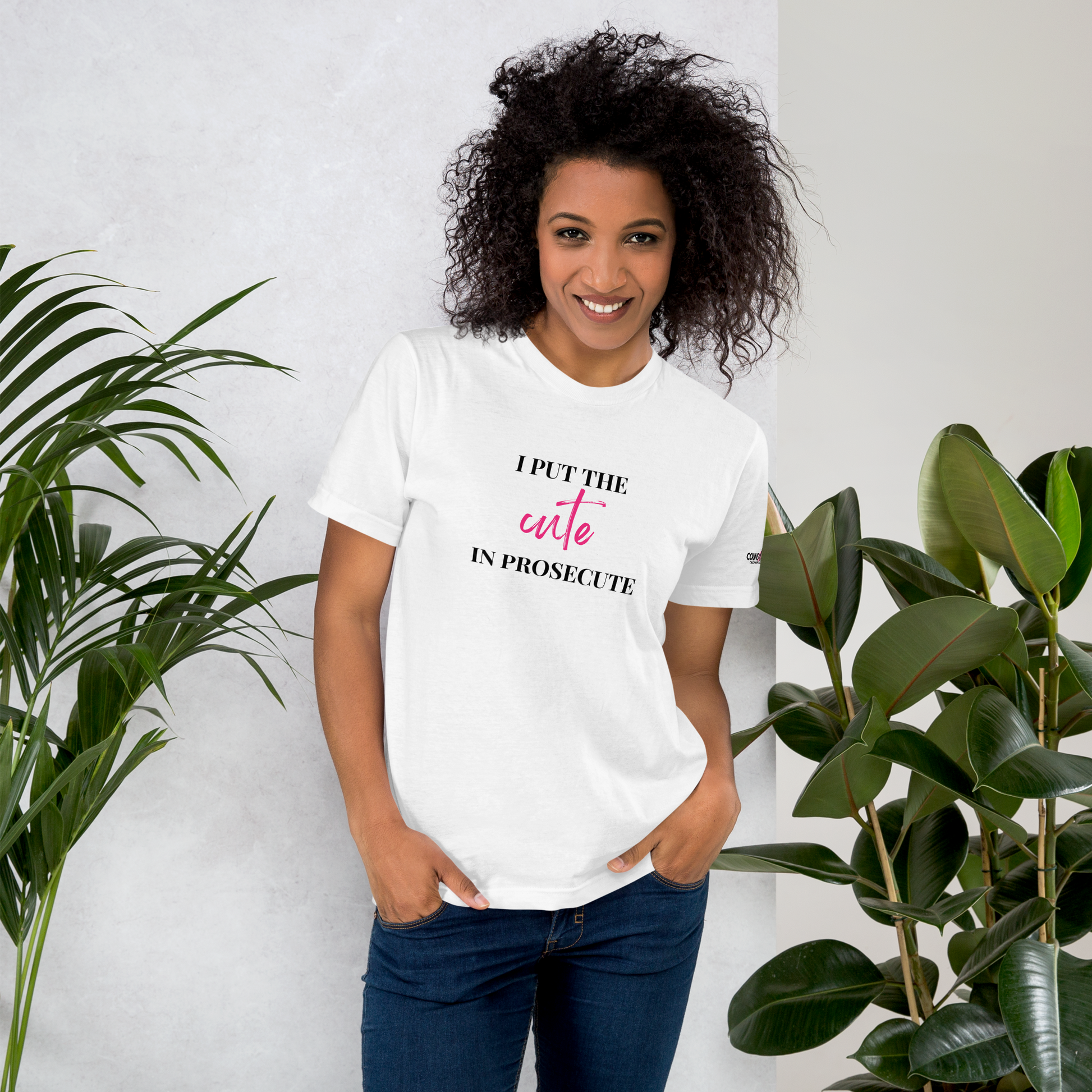 A model wearing a white round-neck tee with the text "I PUT THE CUTE IN PROSECUTE" and the counsellecollection logo on the left sleeve.
