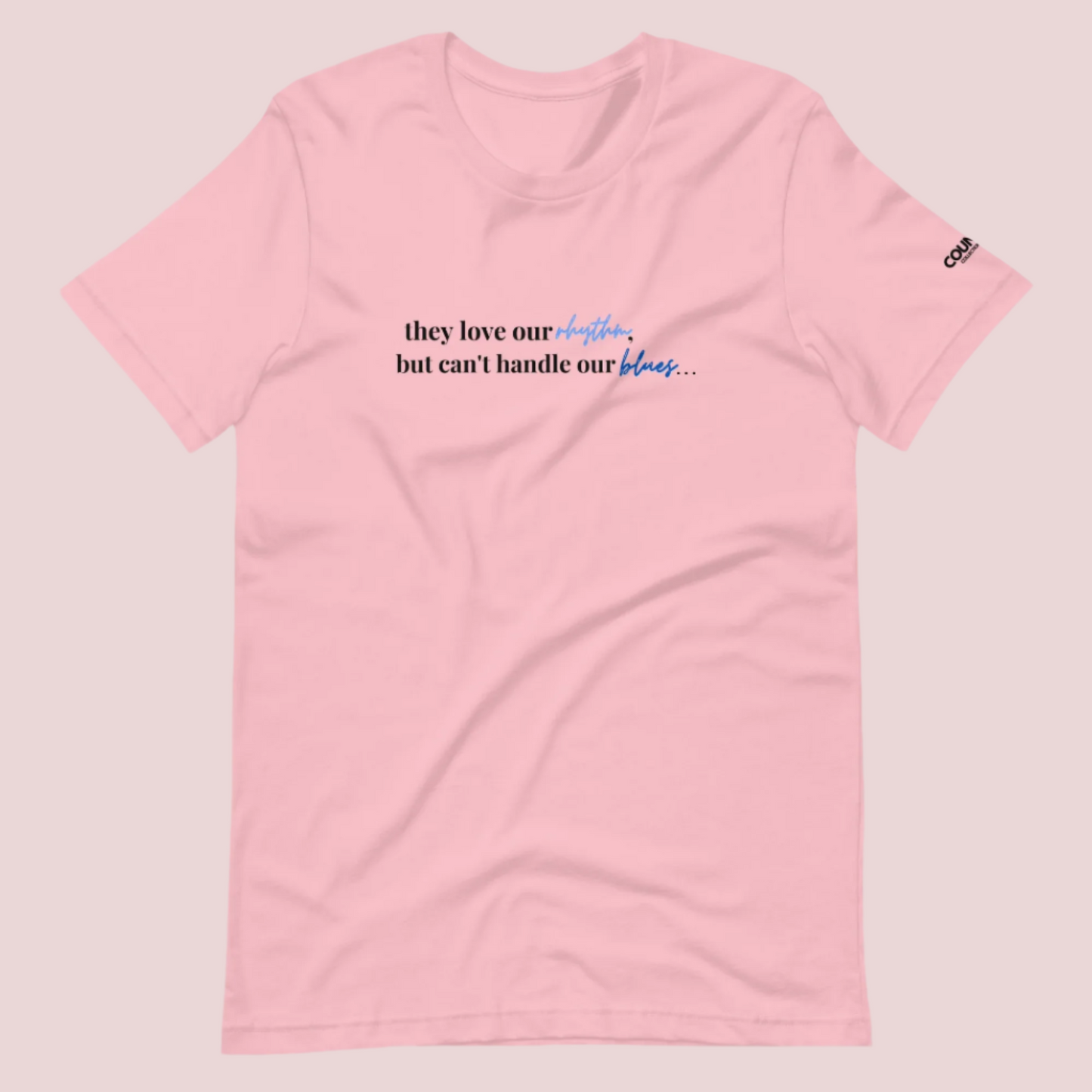 A light pink t-shirt with the text "They love our rhythm, but they can't handle our blues" on the front.