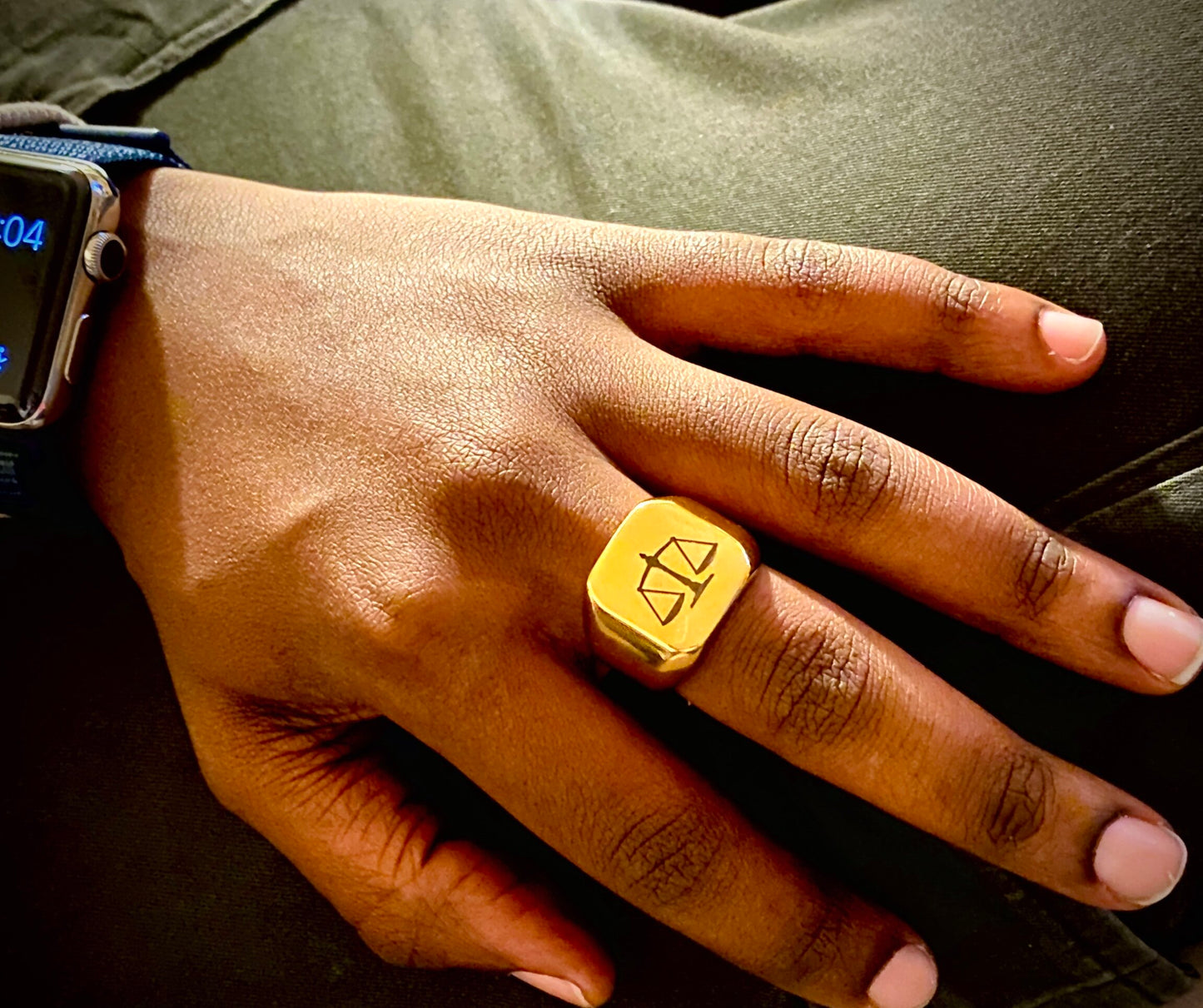 A sleek unisex ring featuring a justice scales emblem. Available in gold and silver.