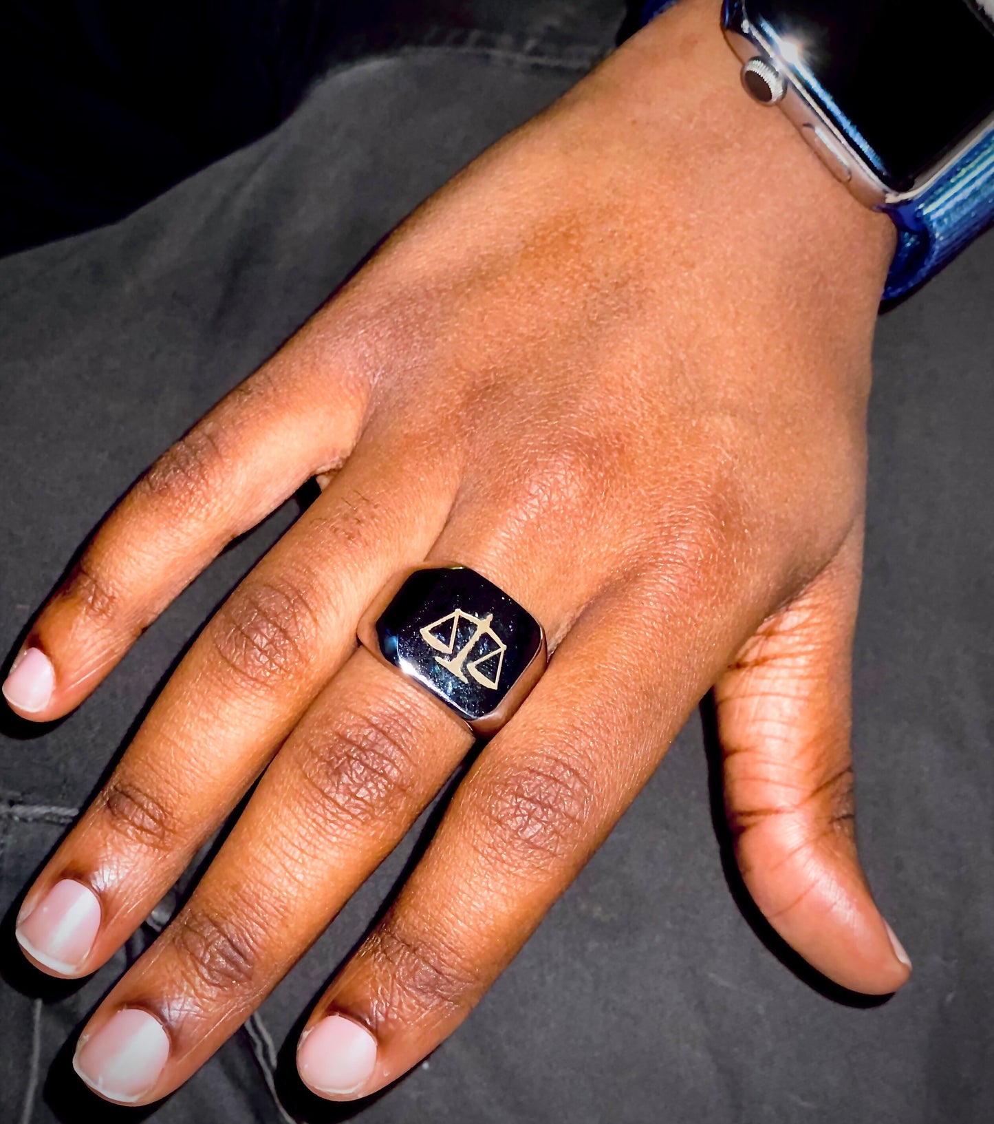 A sleek unisex ring featuring a justice scales emblem. Available in gold and silver.