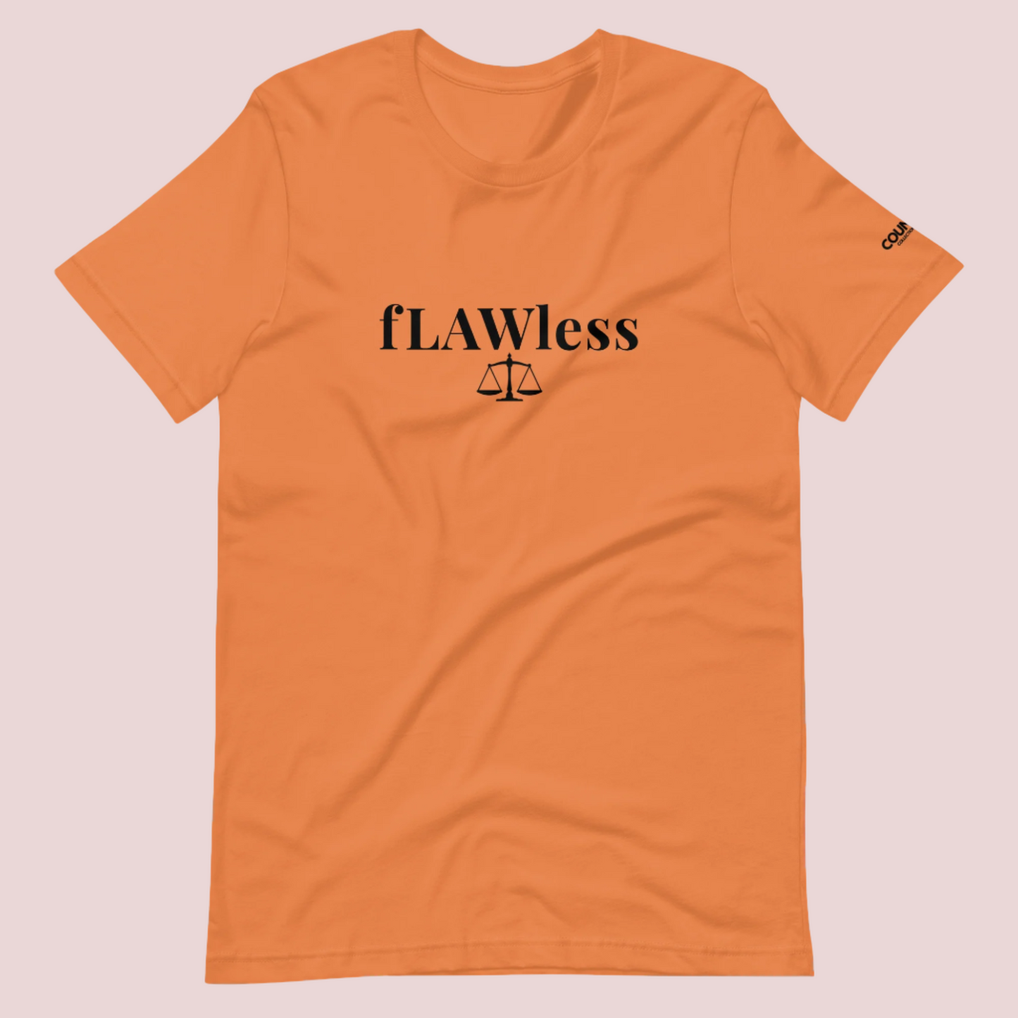 A burnt orange roundneck tee featuring the word "fLAWless", with the letters LAW in uppercase font, with an illustration of justice scales below. The counsellecollection logo is also seen on the left sleeve.