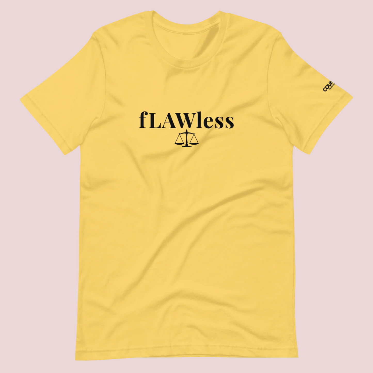 A yellow roundneck tee featuring the word "fLAWless", with the letters LAW in uppercase font, with an illustration of justice scales below. The counsellecollection logo is also seen on the left sleeve.