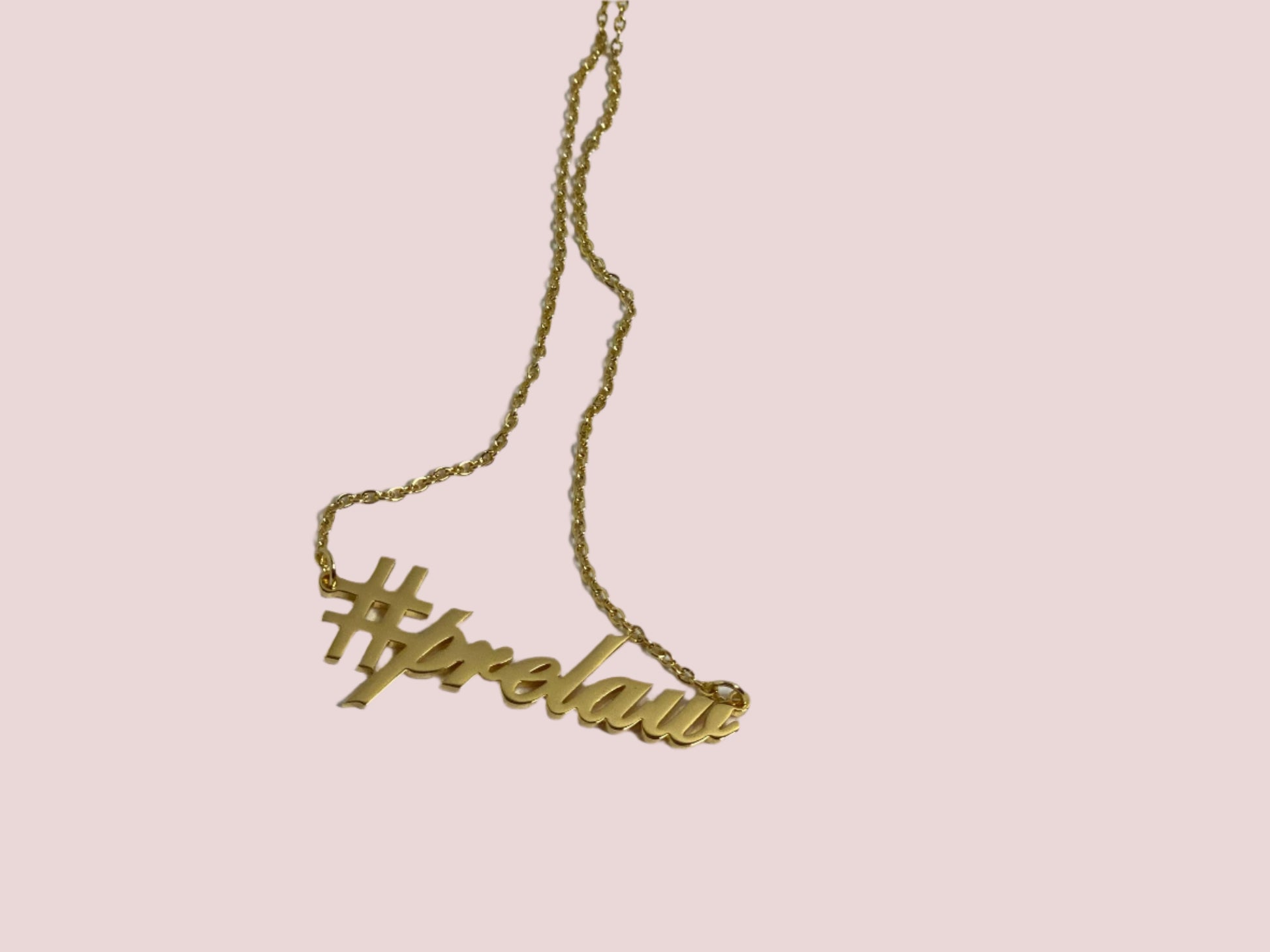 A gold chain necklace featuring the charm "#prelaw" in script font.