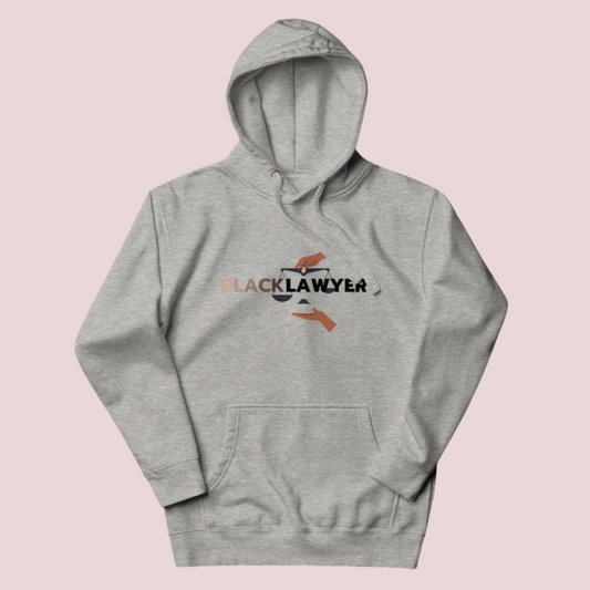 A heather grey hoodie with the words "Black Lawyer" on it and a woman's hand holding an imbalanced justice scale.