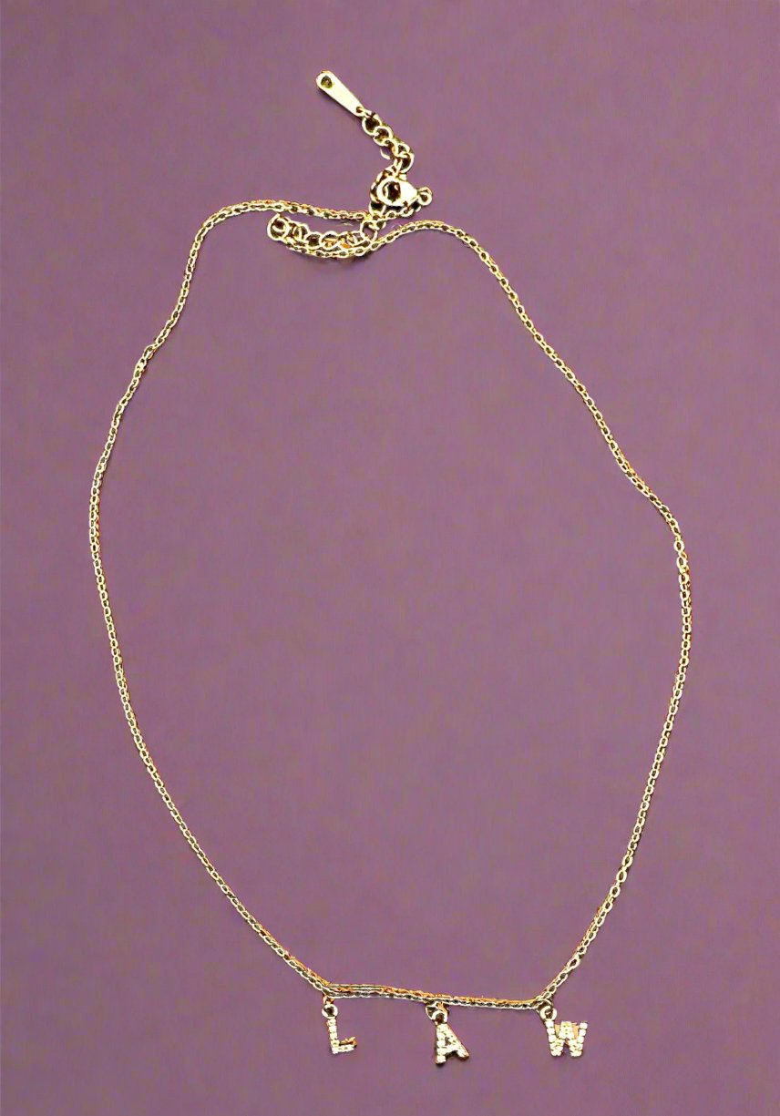 A gold necklace that spells LAW with white stones