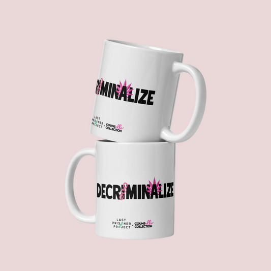 Two white mugs with the text "decriminalize" on the front. Last Prisoner Project and Counselle Collection® logos at the bottom of the mugs. 