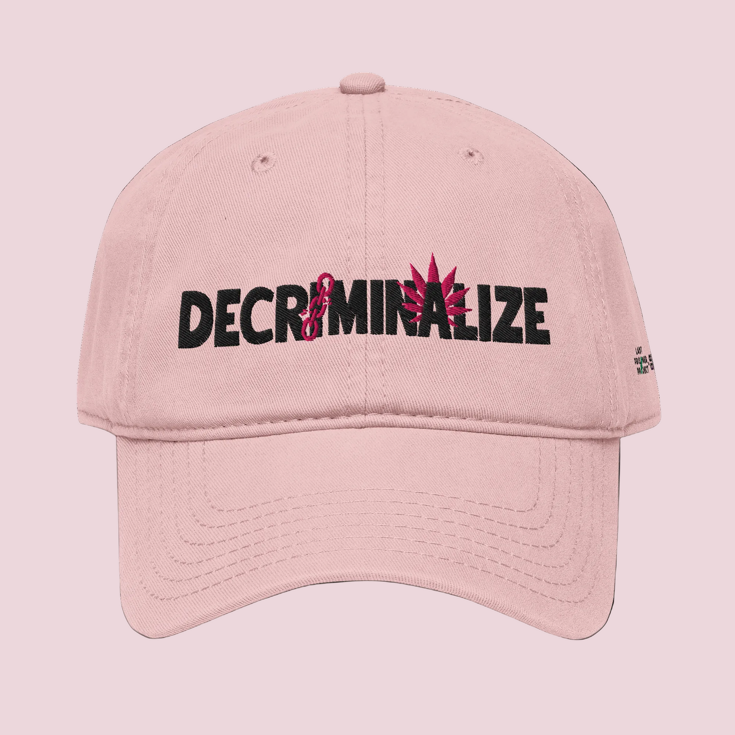 Pink cap with 'DECRIMINALIZE' text and cannabis leaf design on background