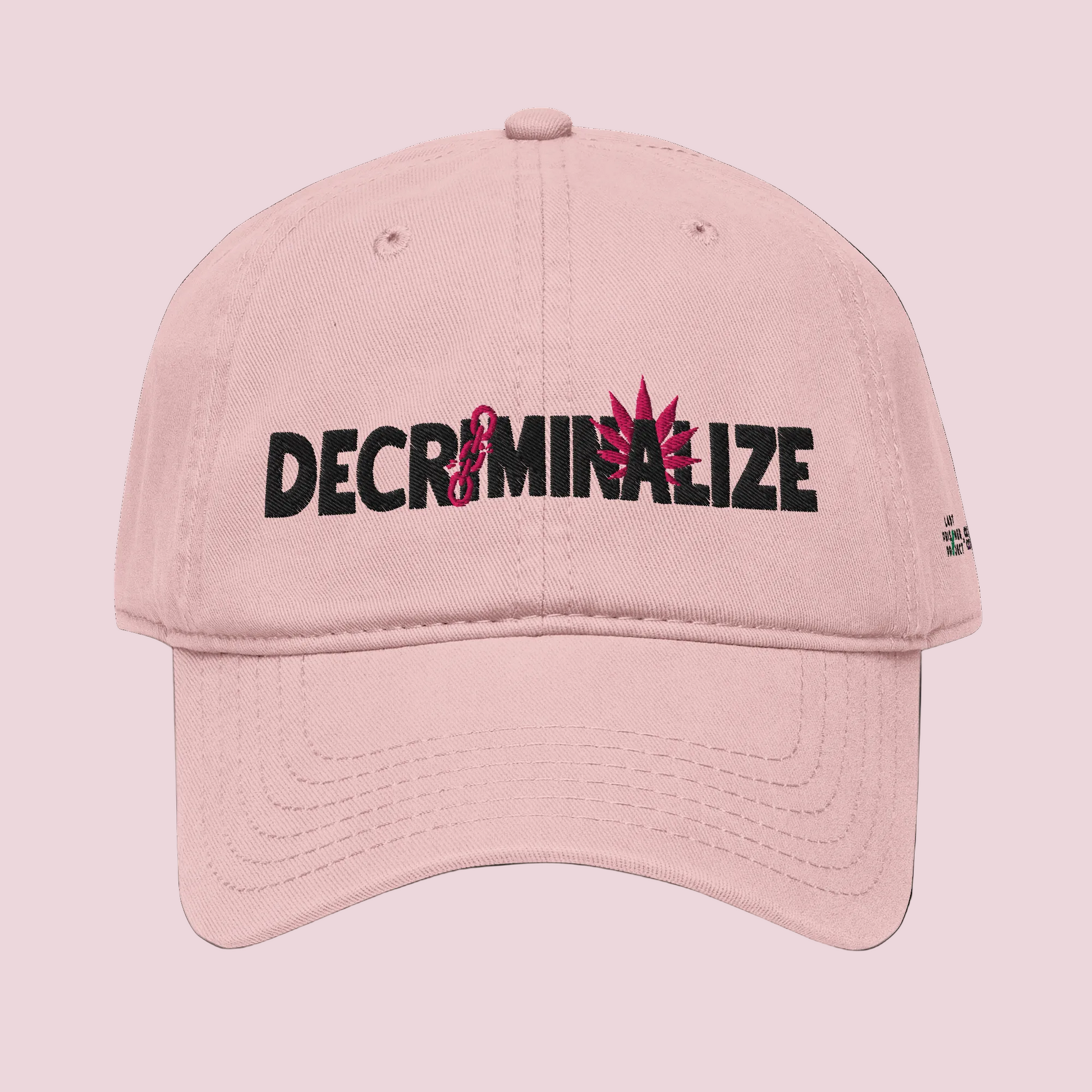 Pink cap with 'DECRIMINALIZE' text and cannabis leaf design on background