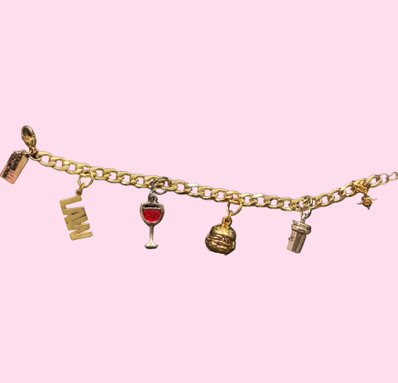 A gold-tone charm chain bracelet displayed horizontally featuring small charms including a the word “LAW”, a wine glass, a hamburger, a coffee cup, and a heart.