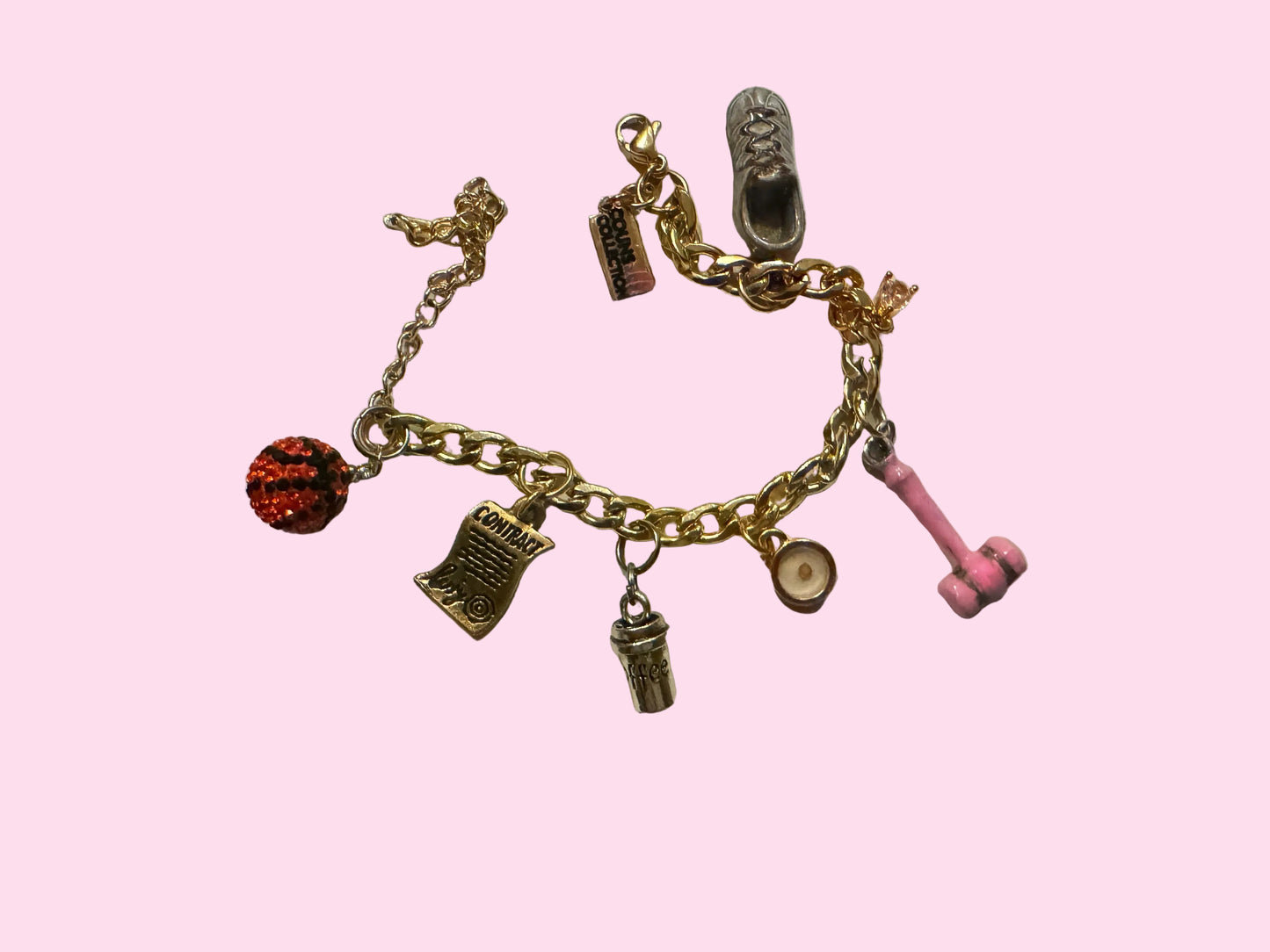 A gold-tone charm bracelet featuring various themed charms including a pink gavel, bedazzled basketball, signed contact, shoe, and other small icons