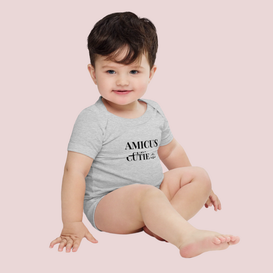 An infant onesie featuring the words "AMICUS CUTIE", with an envelope neckline and three-snap leg closure for easy changing. Available in bubblegum pink, heather grey, white, and mellow yellow, and in sizes 3-6m, 6-12m, 12-18m and 18-24m.
