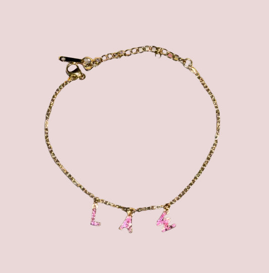 A bracelet with the word "LAW" in hot pink stones as charms.