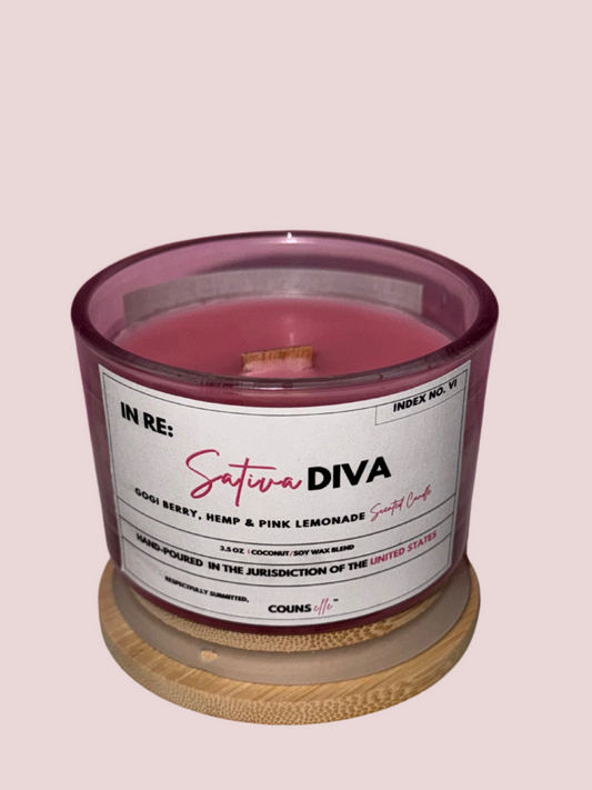 A candle in a glass container with a white label featuring the text "INDEX NO. VI", "IN RE:", "SATIVA DIVA", "GOGI BERRY, HEMP & PINK LEMONADE SCENTED CANDLE", "3.5 oz", "COCONUT/SOY WAX BLEND", "HAND-POURED IN THE JURISDICTION OF THE UNITED STATES", "RESPECTFULLY SUBMITTED", with the counsellecollection logo at the bottom of the design