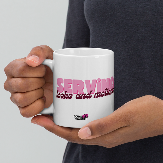 a white, 11oz mug featuring the words "serving looks and motions" in pink and burgundy letters. 